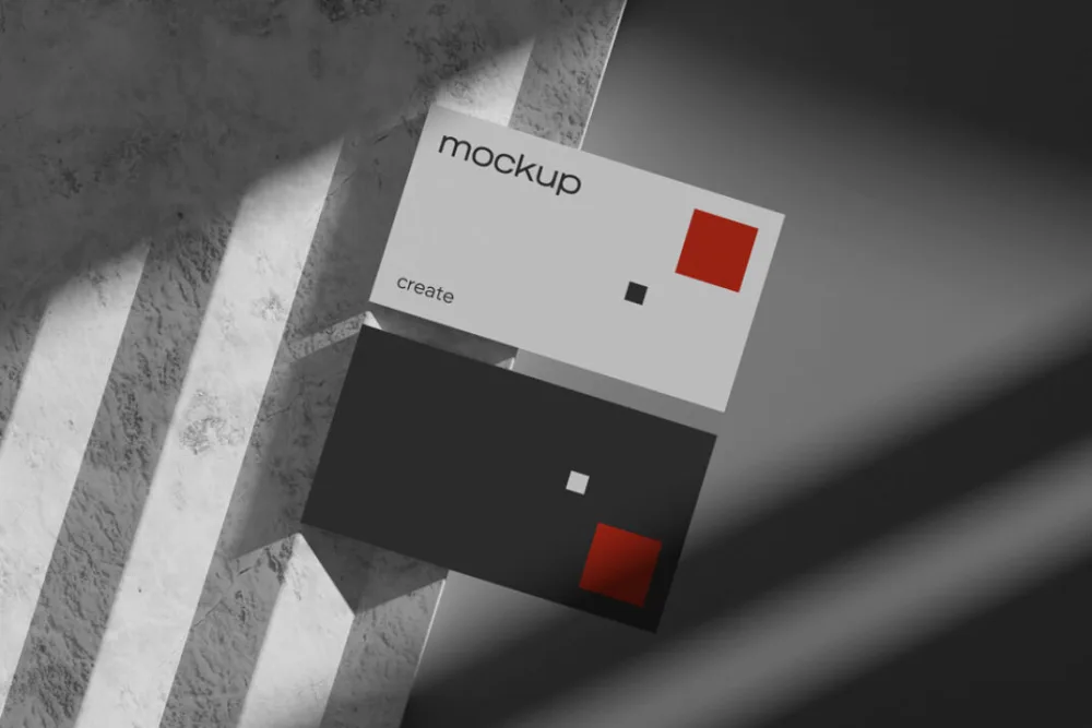 Modern business card mockup with minimalist red and black geometric accents. The cards are displayed on a textured marble surface under dramatic lighting with sharp shadows.