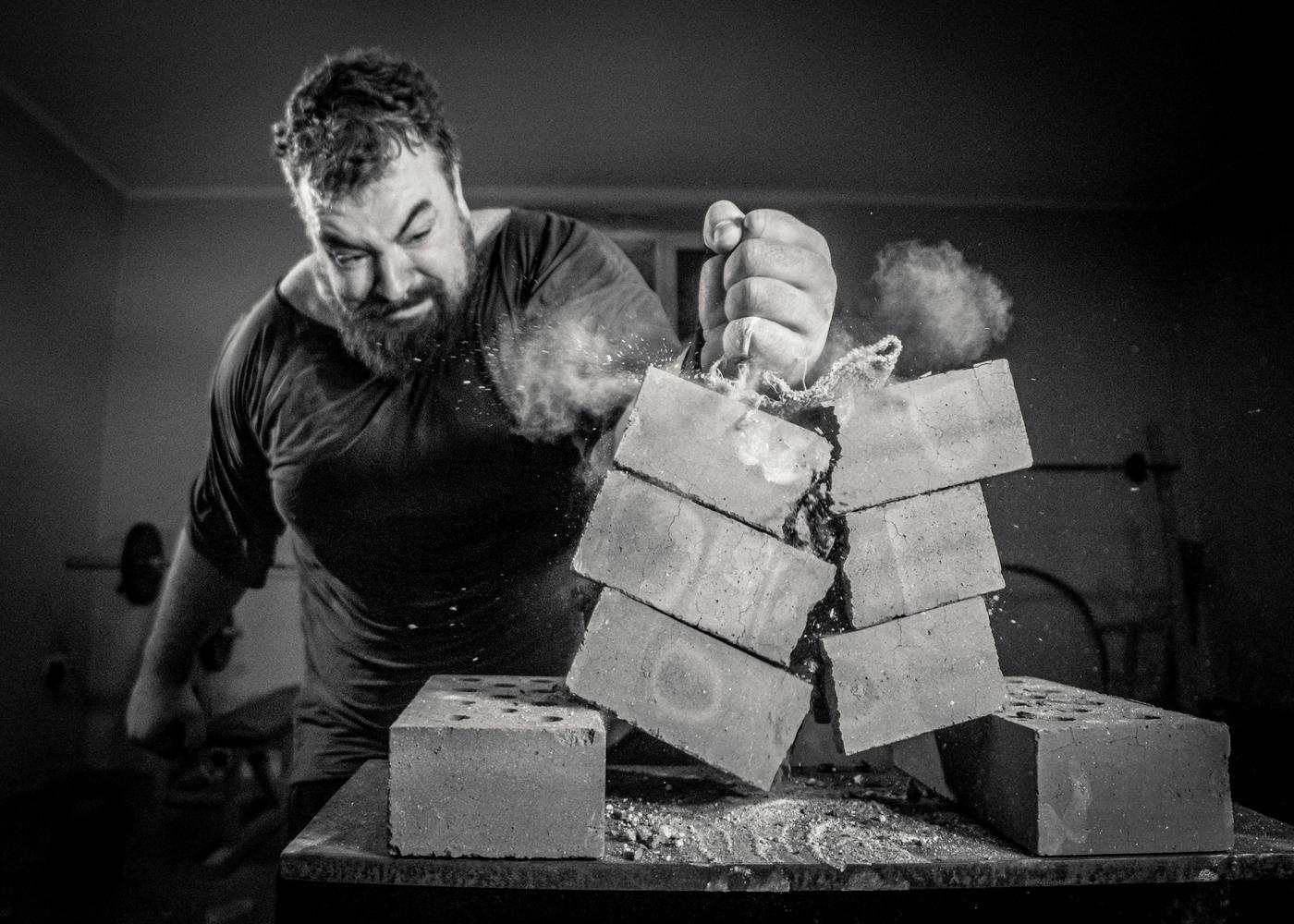 Low testorone symptoms - B&W image of a man breaking bricks with his hand