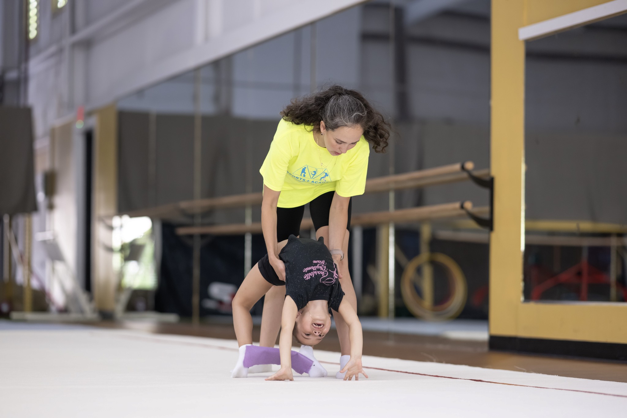 Girl from beginner group being assisted in her bridge or back bend with the assistance of one of our assistant coaches