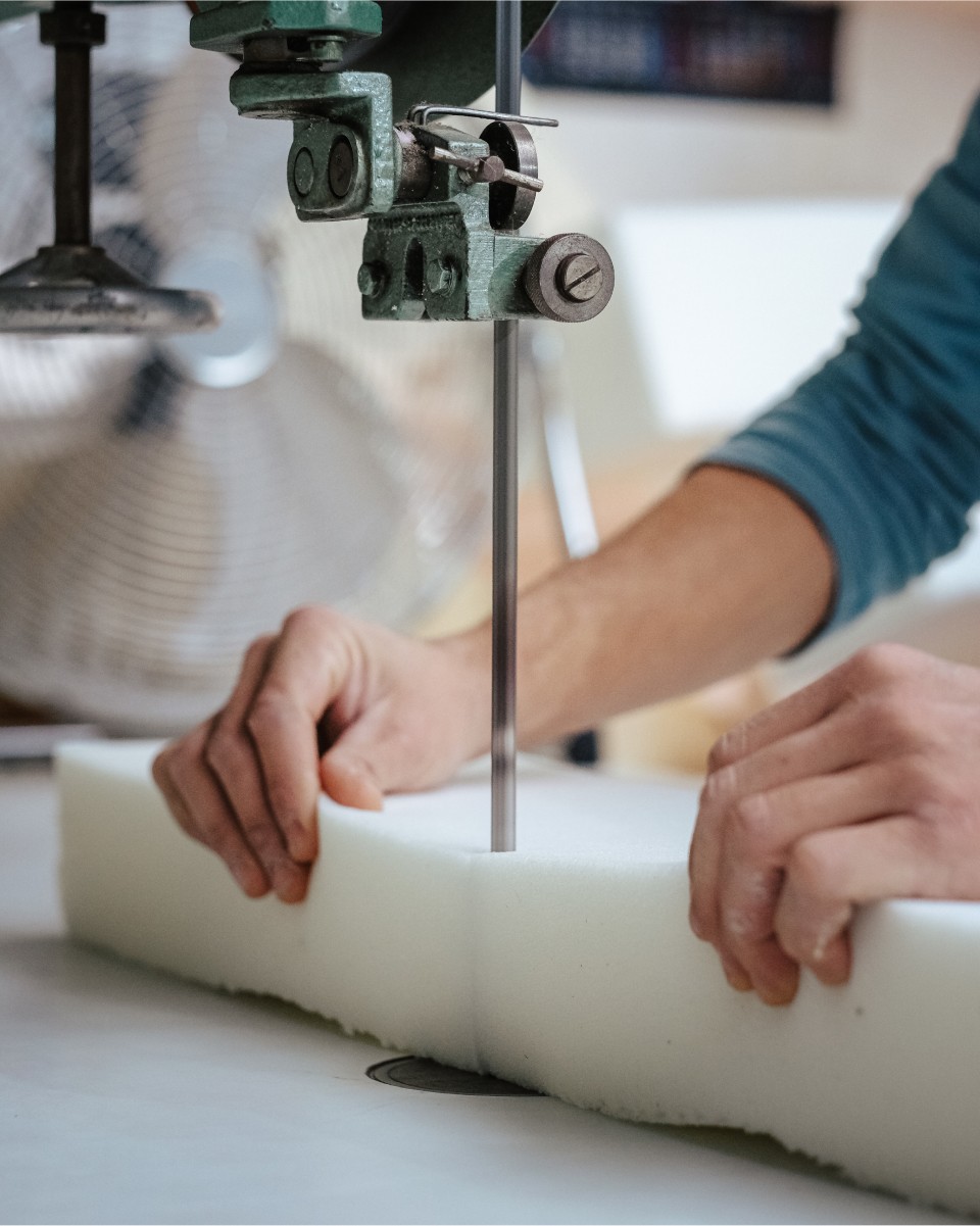 Händer som skär en skumplast med en bandsåg