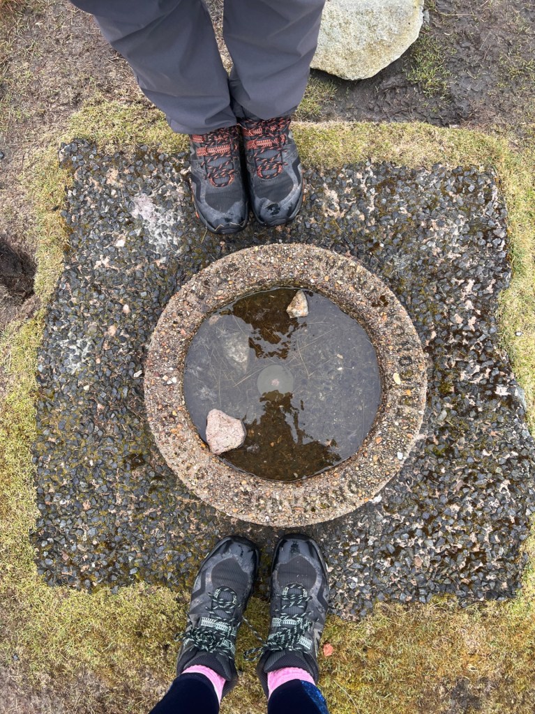 Martin and April's feet either side of the summit cairn at Branstree Fell.