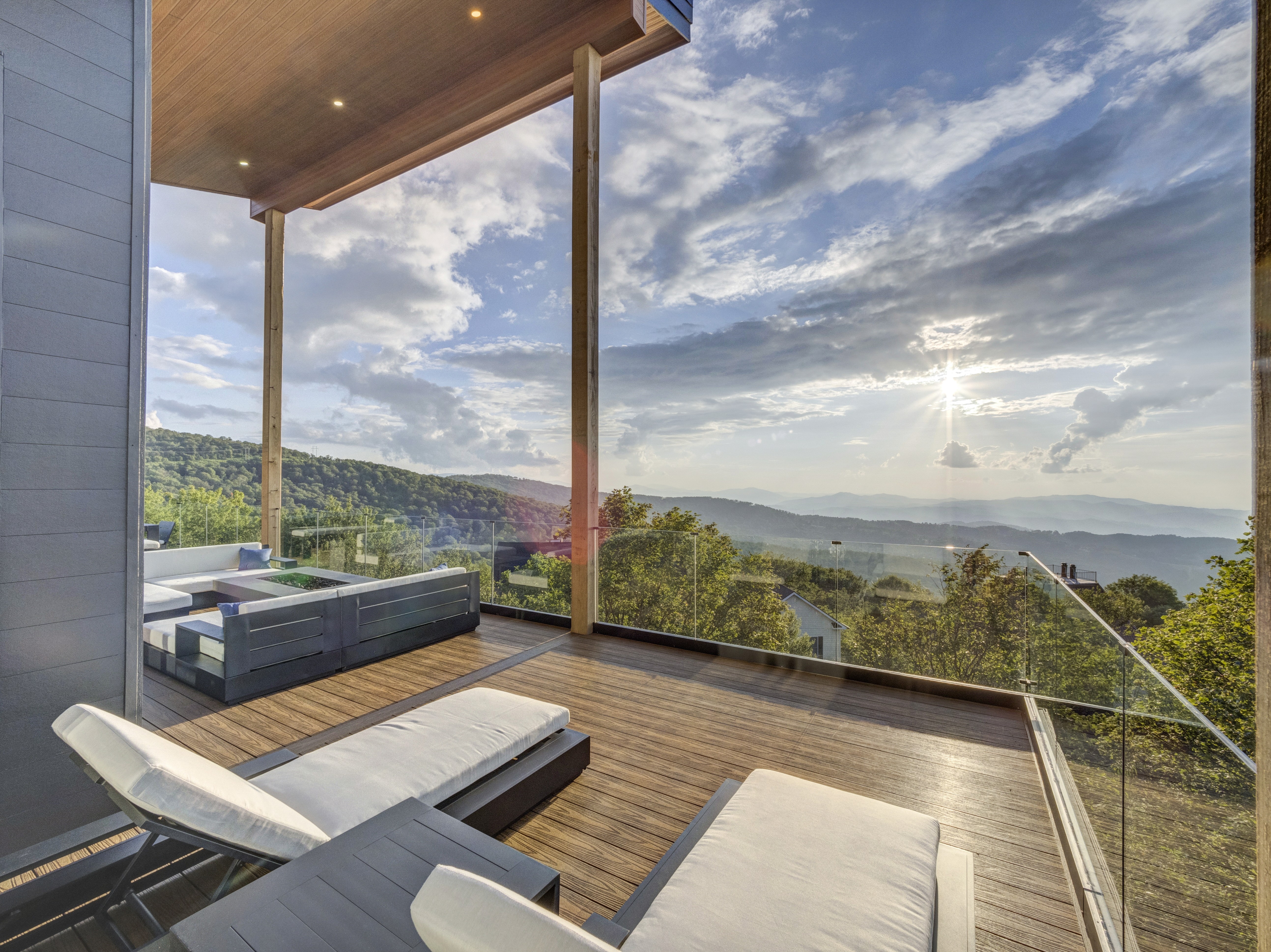 Two white modern lounge chairs on a high-end balcony, positioned for a front-row view of a mountain sunset