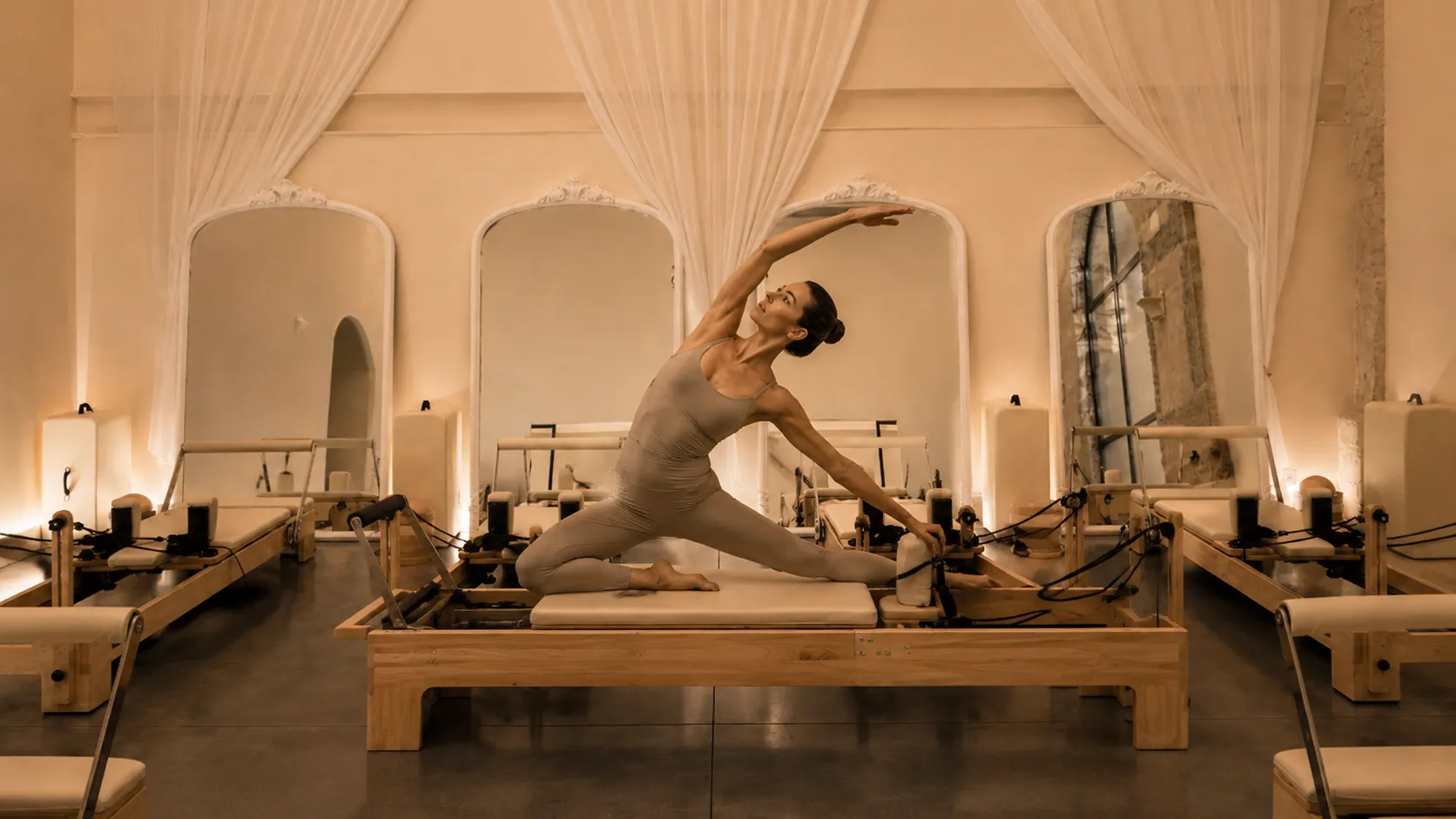 Femme réalisant un étirement latéral sur une machine de Pilates Reformer au sein du studio Samnaïa à Saint-Chamond.