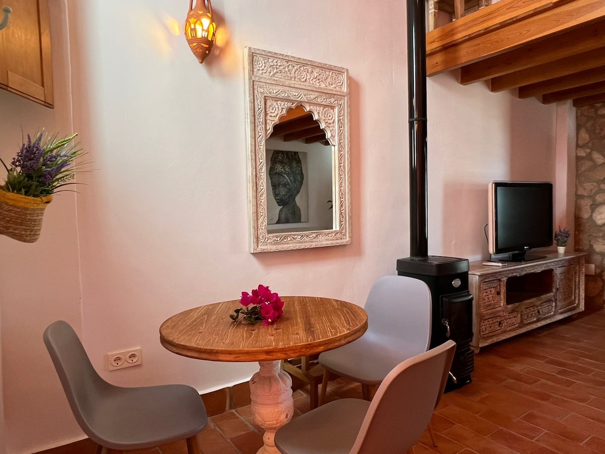Comedor con mesa redonda junto a la chimenea de leña