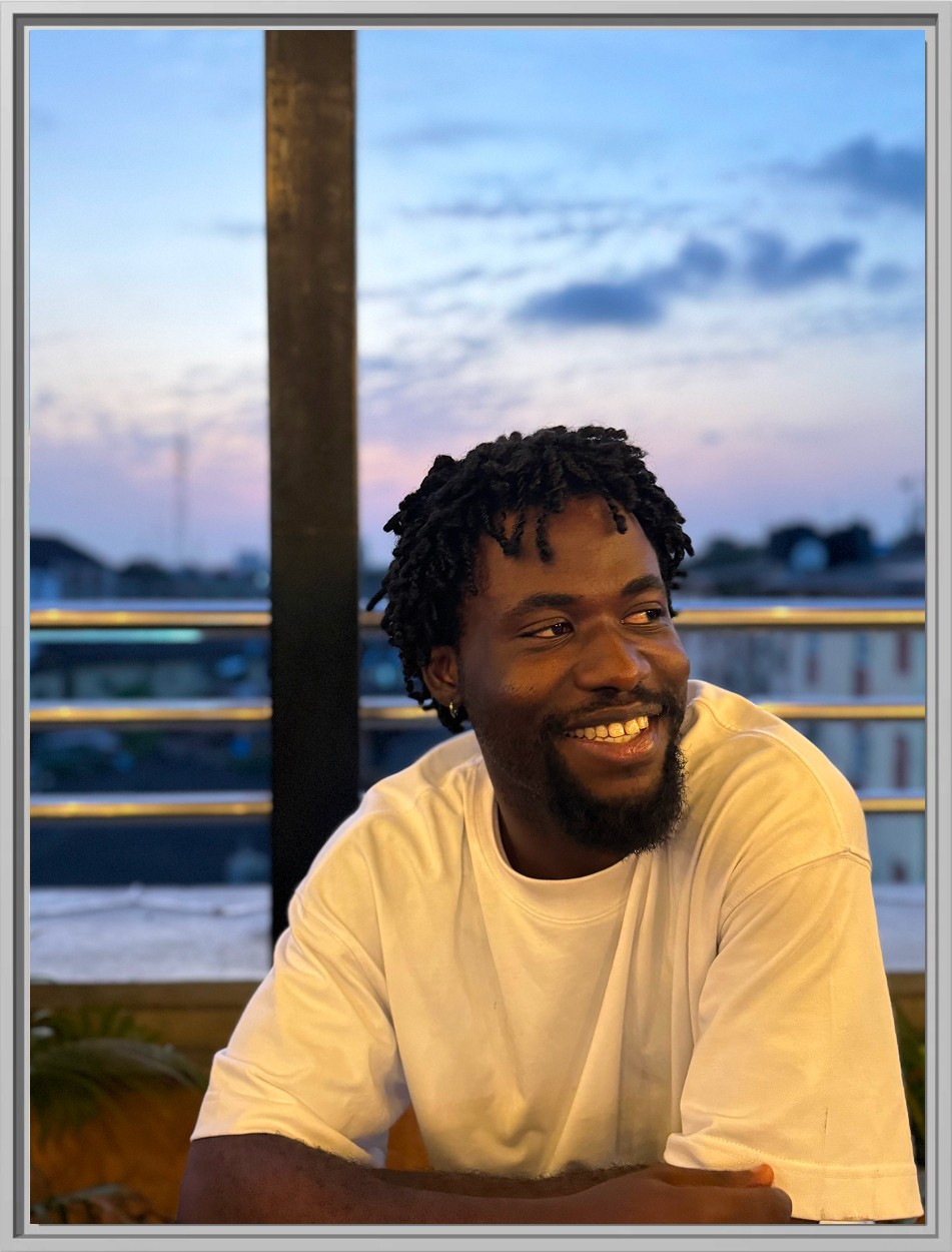a picture of michael adekolu in a white shirt, smiling and looking sideways