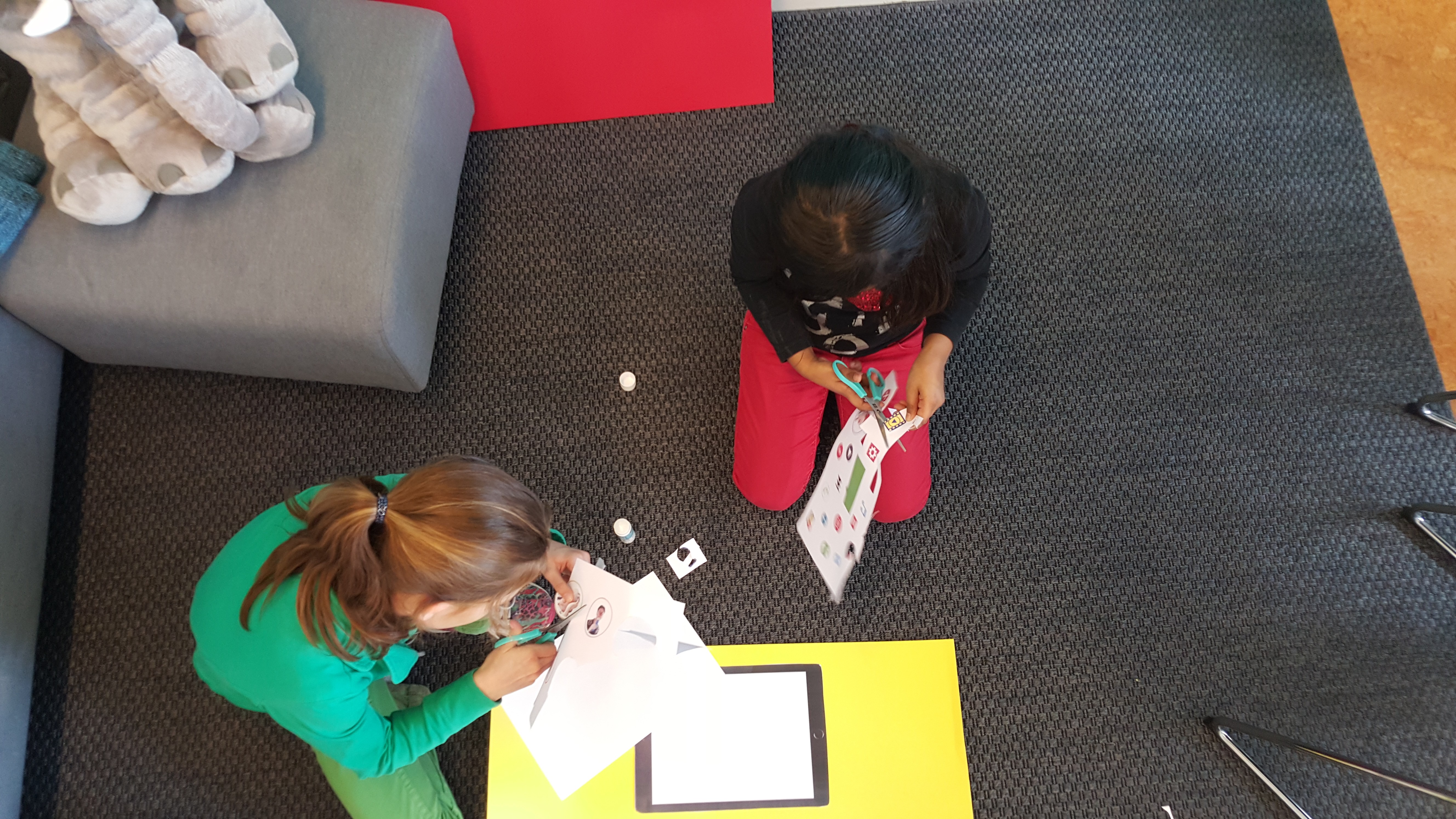 Kinderen knutselen samen op de grond hoe de CliniClowns app eruit kan komen te zien.