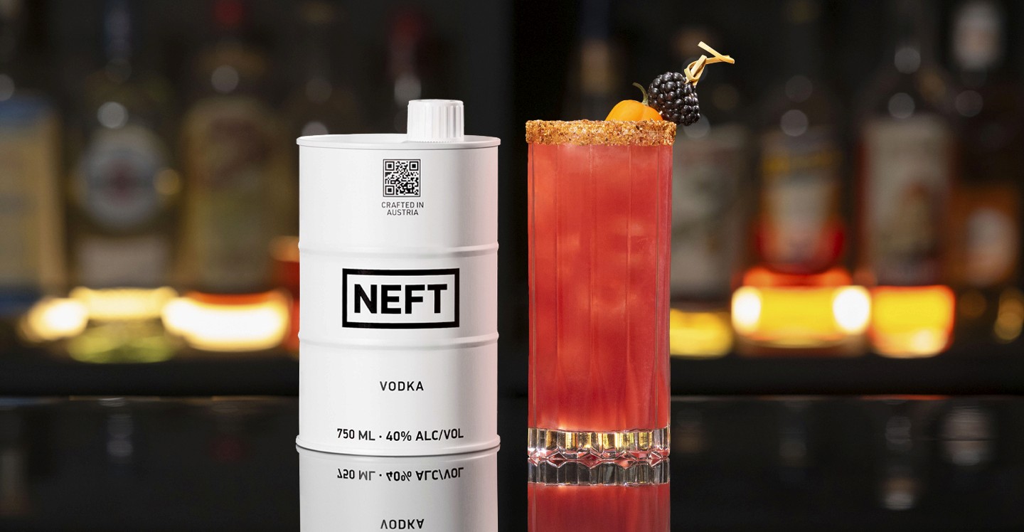 A NEFT Vodka Barrel and a glass of Blackberry Bridge on a bar counter.