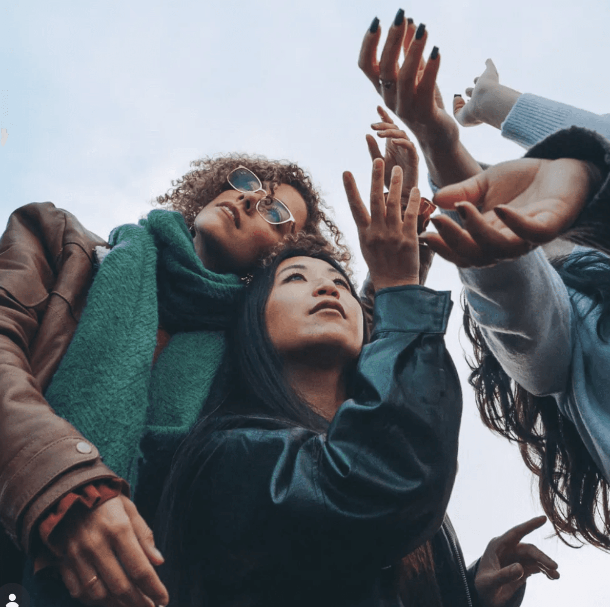 Four friends reaching upwards