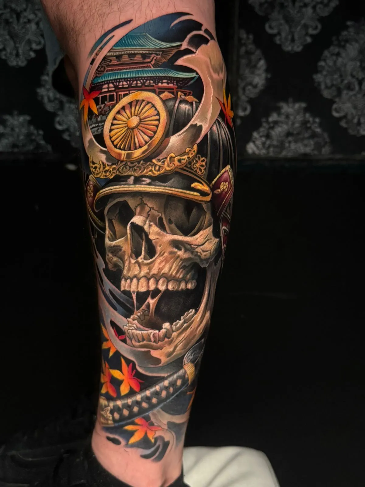 Color Japanese skull tattoo on lower leg with temple and autumn leaves at Calavera Ink Berlin