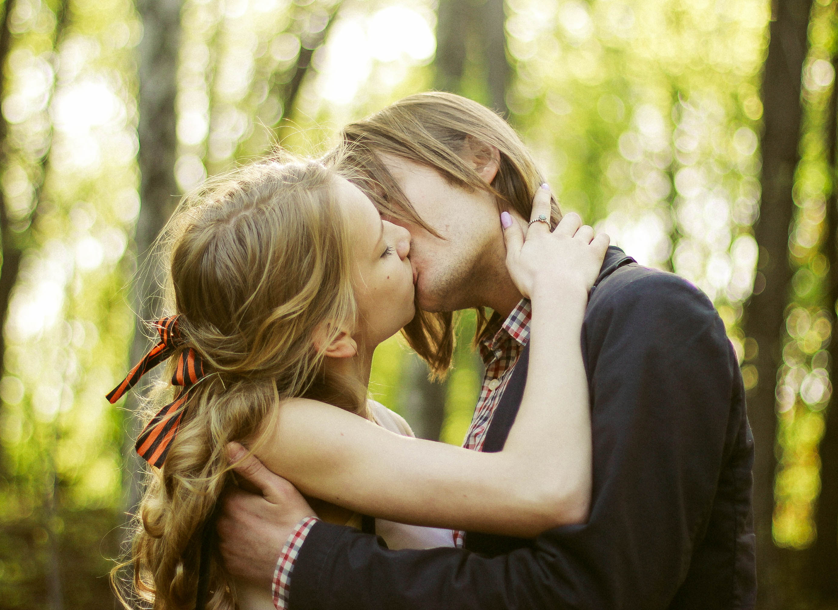 A couple in wedding attire walks hand in hand across a sunlit field.