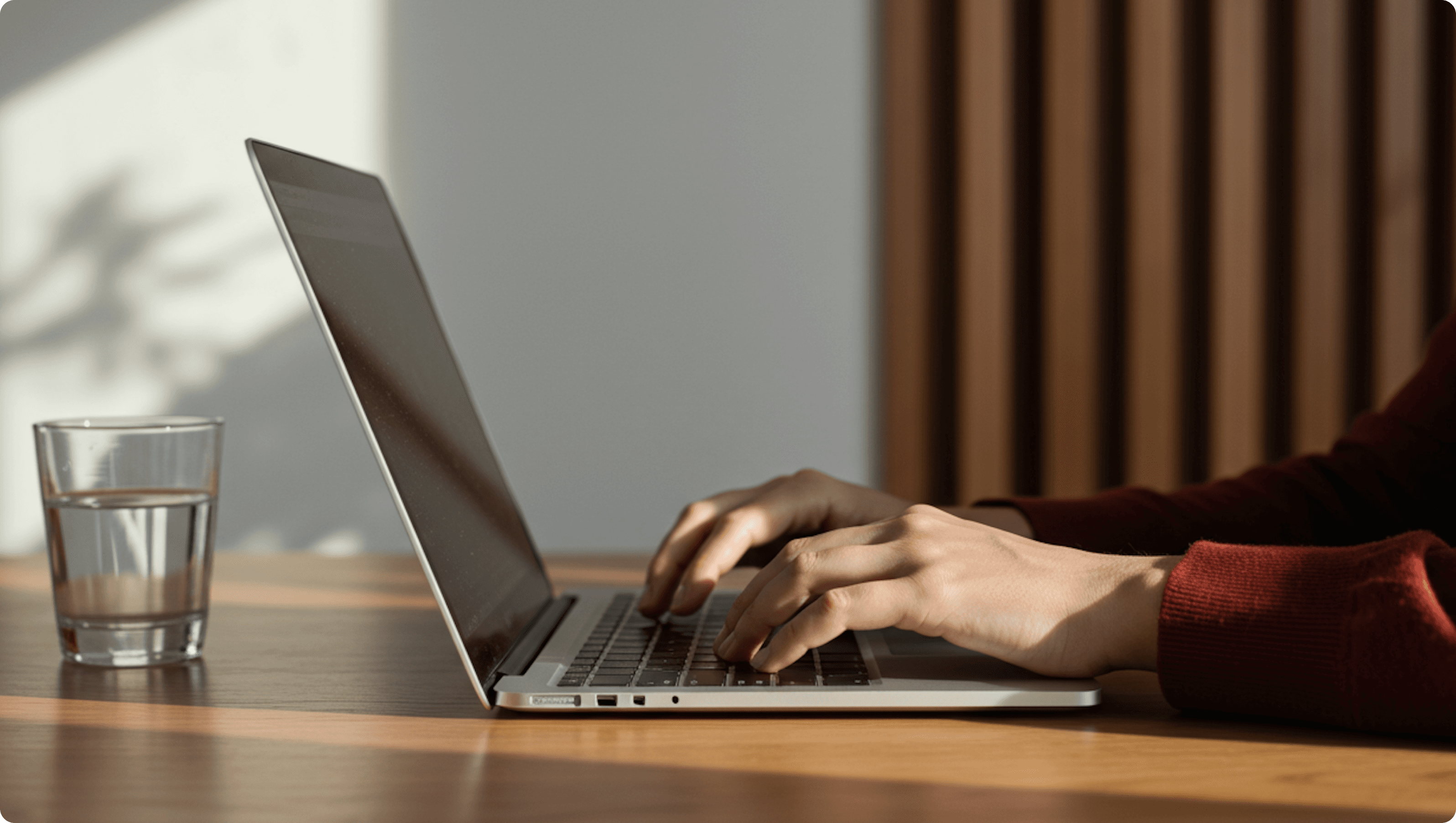Person typing on a laptop at a wooden desk