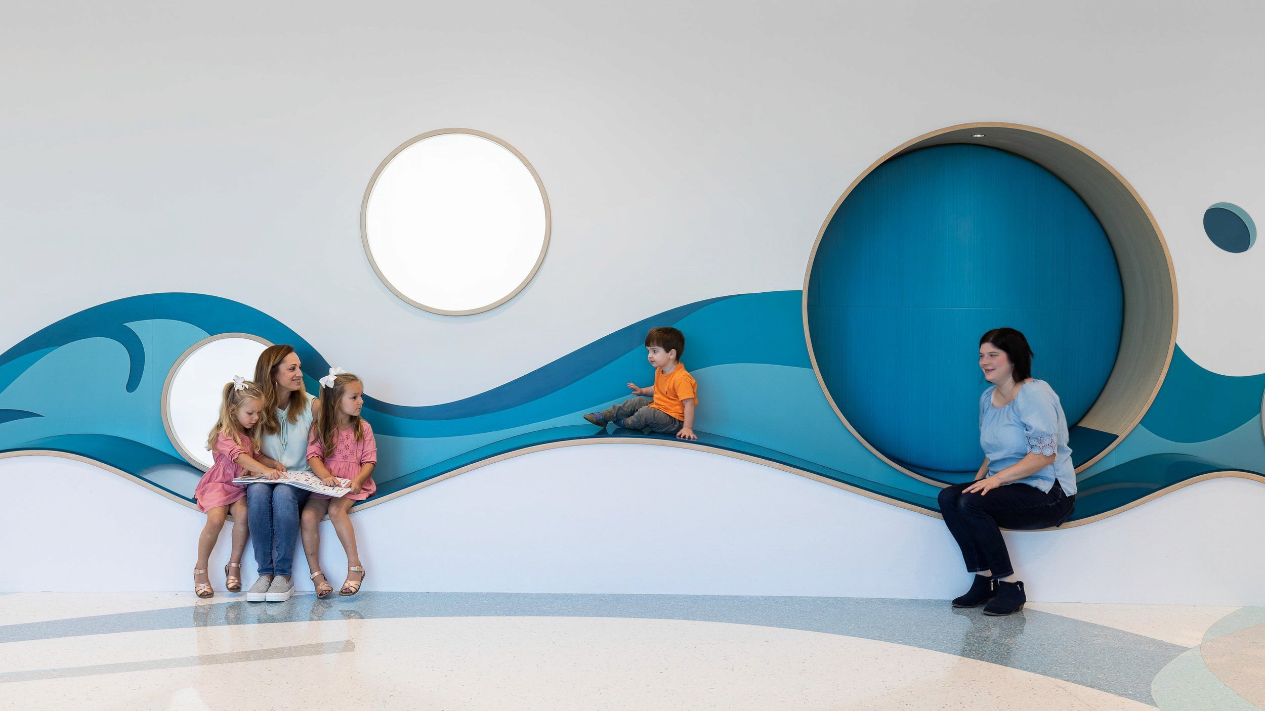 Adults with children sitting on wave-like bench