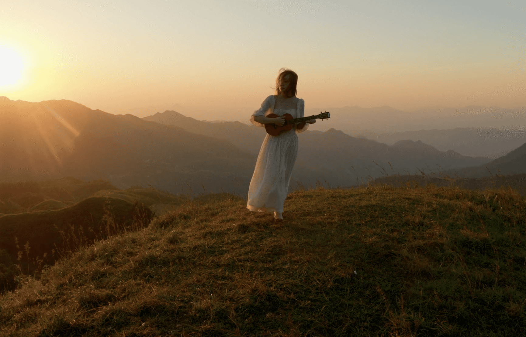 A woman in a field playing guitar