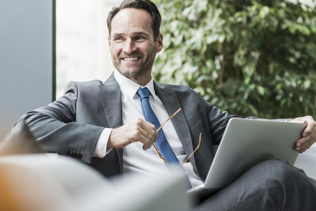 Person Smiling seated at lounge with laptop open