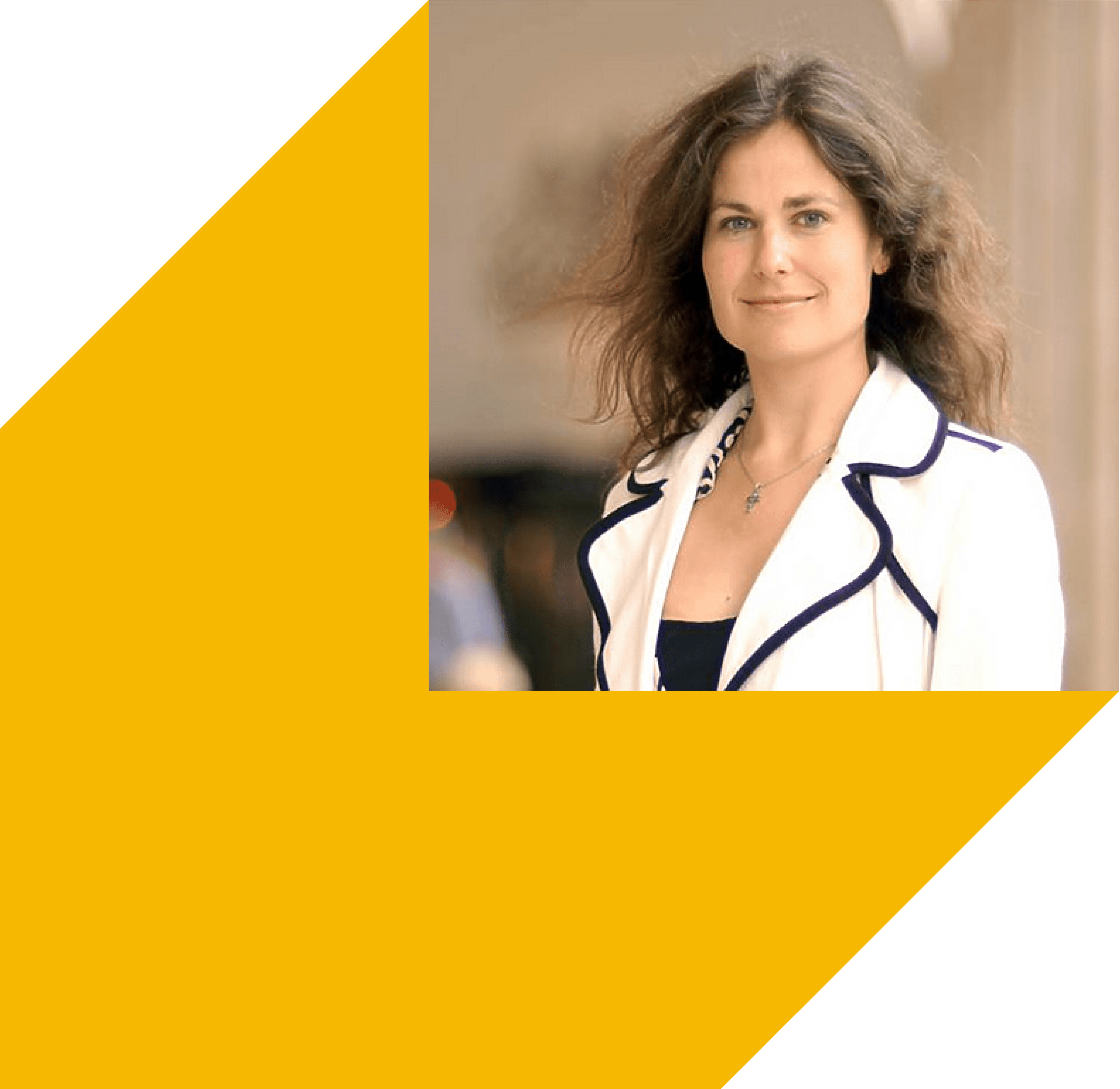 A woman in a stylish outfit stands outdoors, smiling with windswept hair against a blurred background.