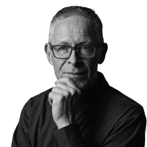 Black and white portrait of Nik Sliwerski, resting his chin on his hand and looking at the camera