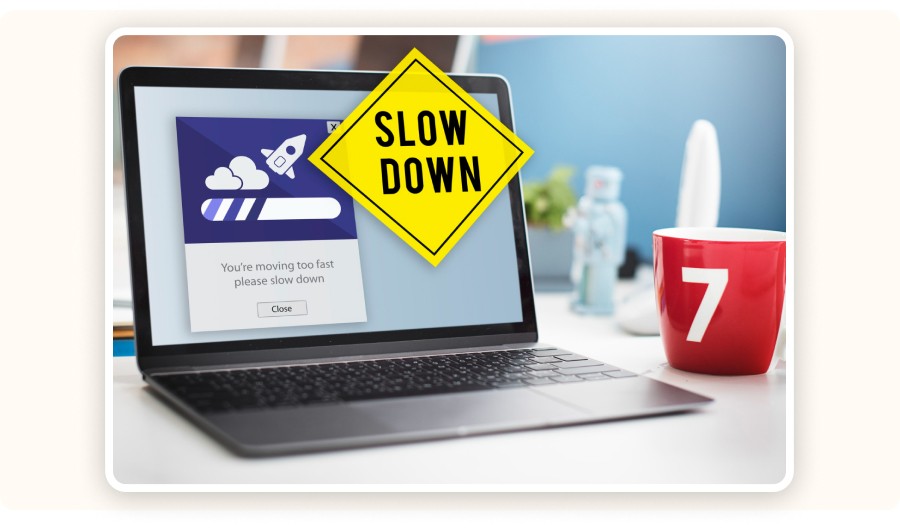 Laptop showing slow loading warning with slowdown sign and coffee mug