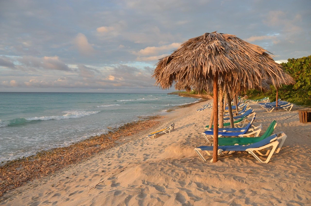Playa paradisíaca con sombrillas de paja y reposeras sobre la arena, ideal para turistas que buscan comodidad y facilidad al realizar su pago con Pix en Brasil