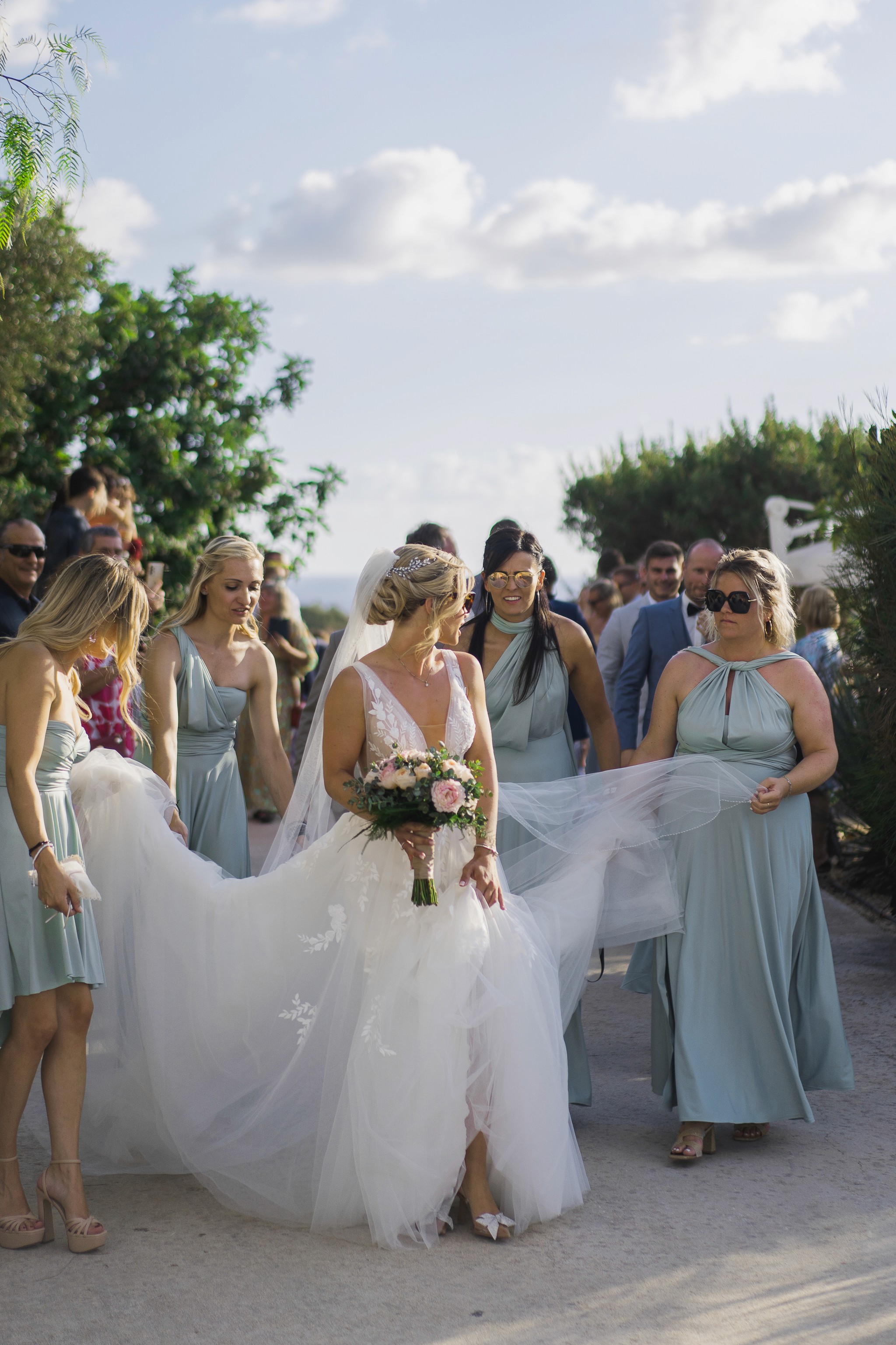 Νύφη που περπατάει με τις παράνυμφες της σε destination wedding στην Ελλάδα