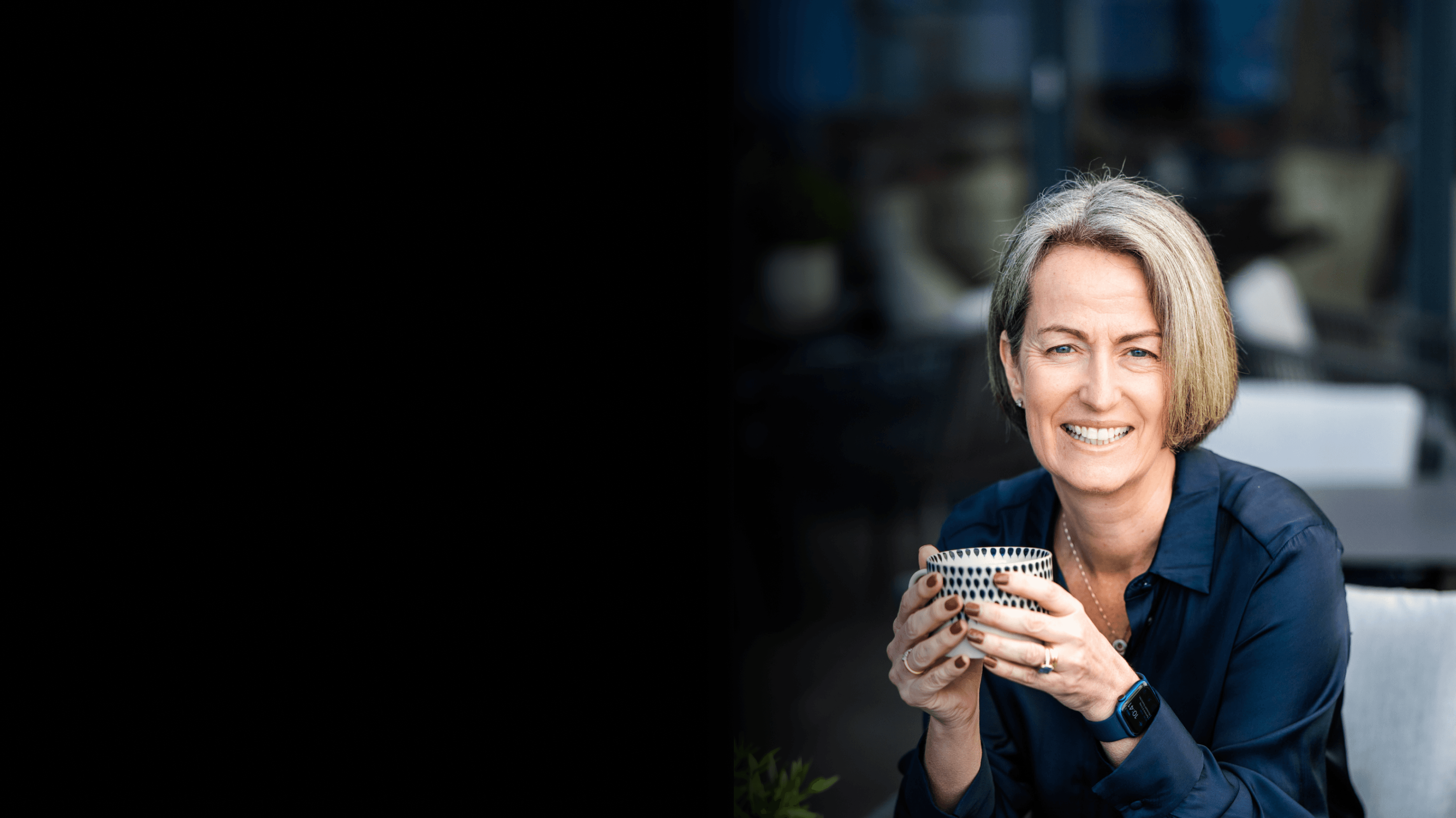 Kate sitting with a tea cup in hand with some greenery in the background