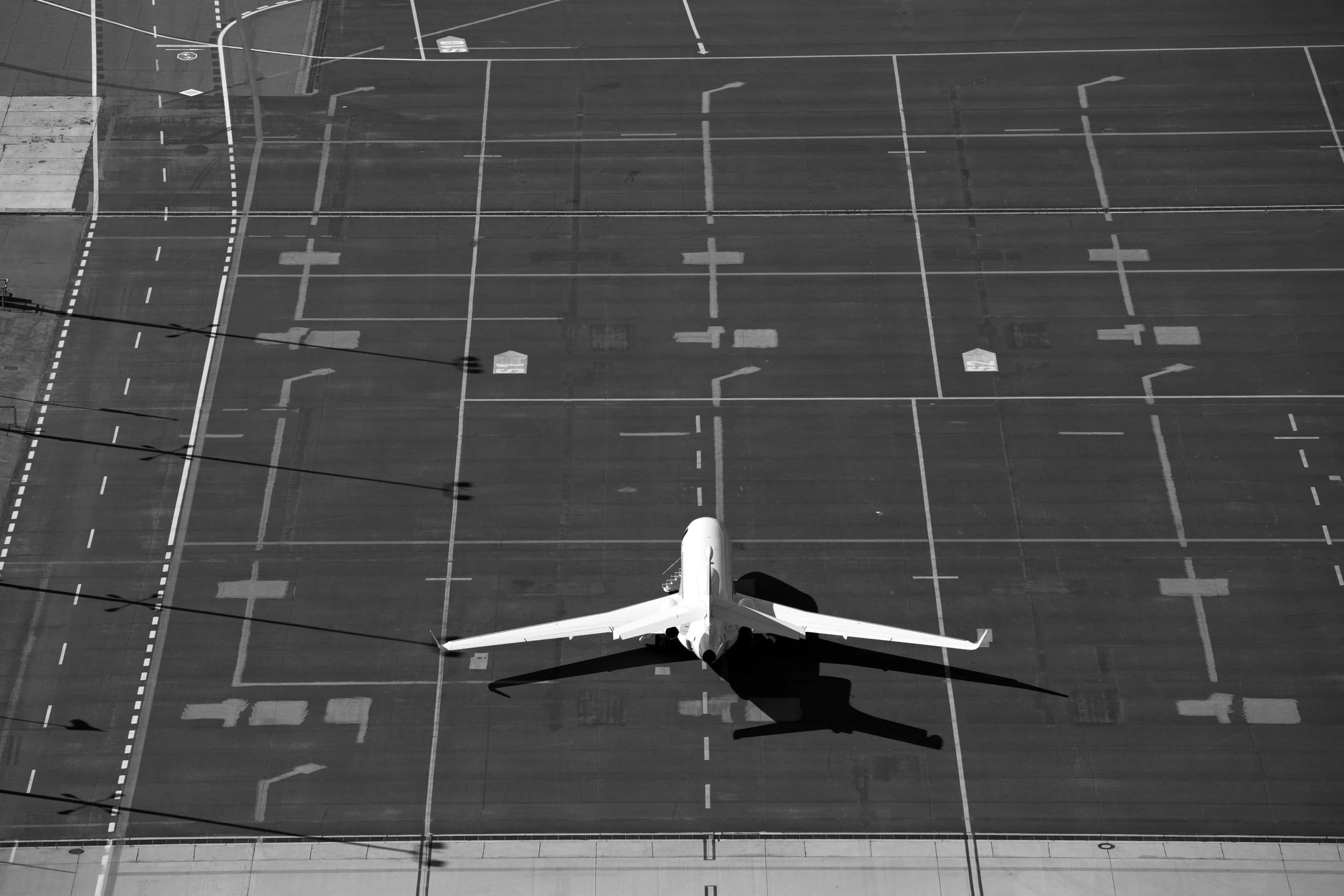 Aerial view of a plane flying over a grid-like surface in black and white.