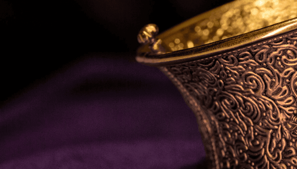 Close-up of handcrafted antique gold bangle with intricate floral carvings and gemstone detailing by Jora Jewellers.