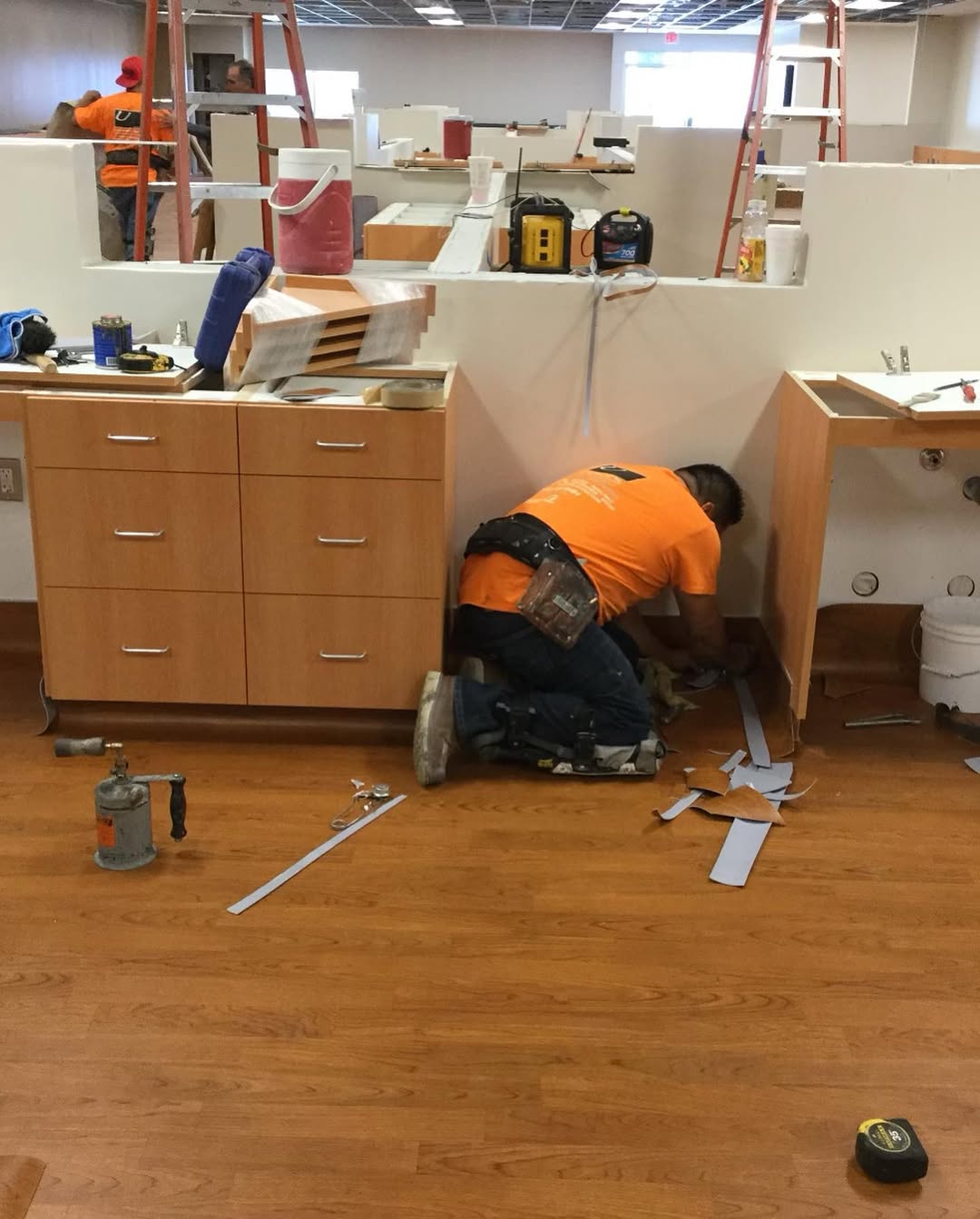 Installer fitting sheet vinyl around built-in casework