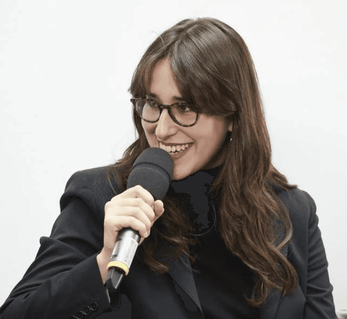 Frau mit langen braunen Haaren spricht in ein Mikro