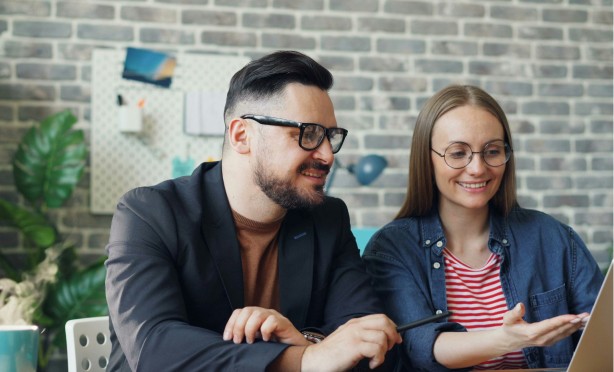 A man and a woman in an office, looking at a screen