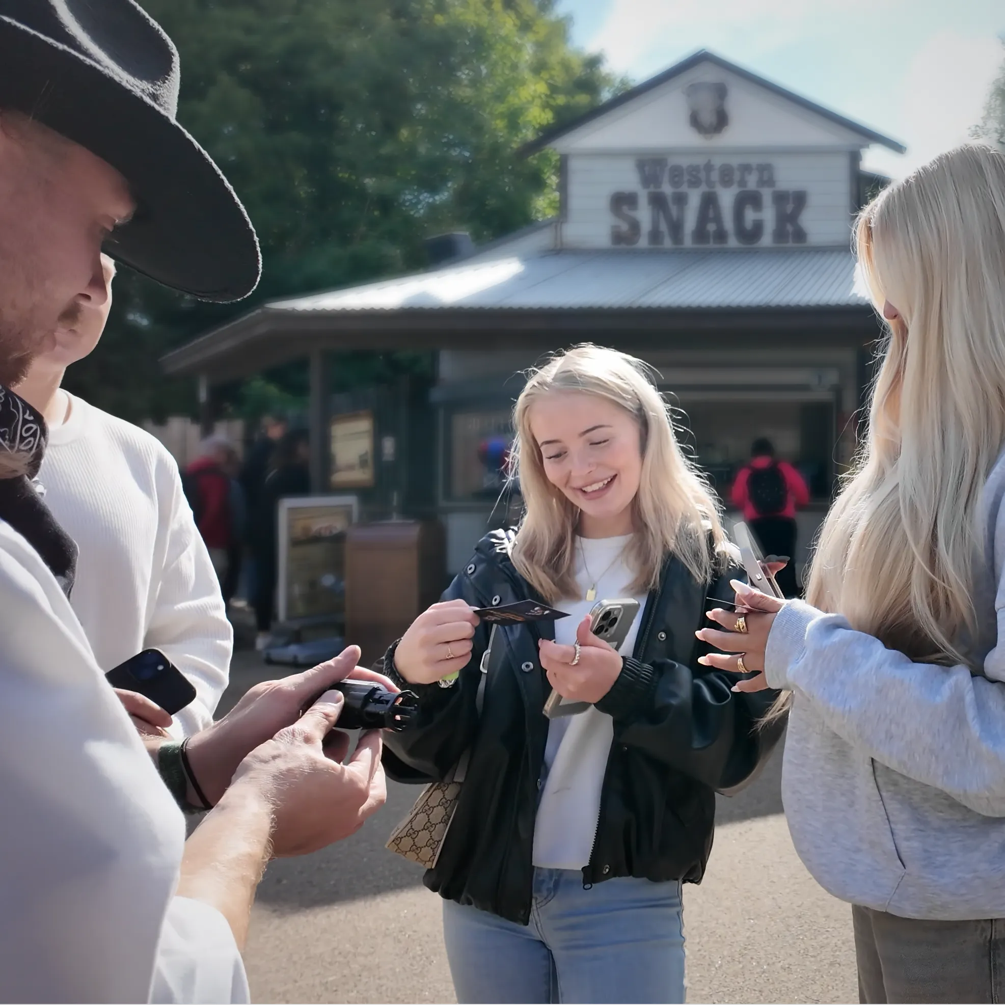 Guest smiling as she receives a voucher at a Western Snack kiosk, phone in hand