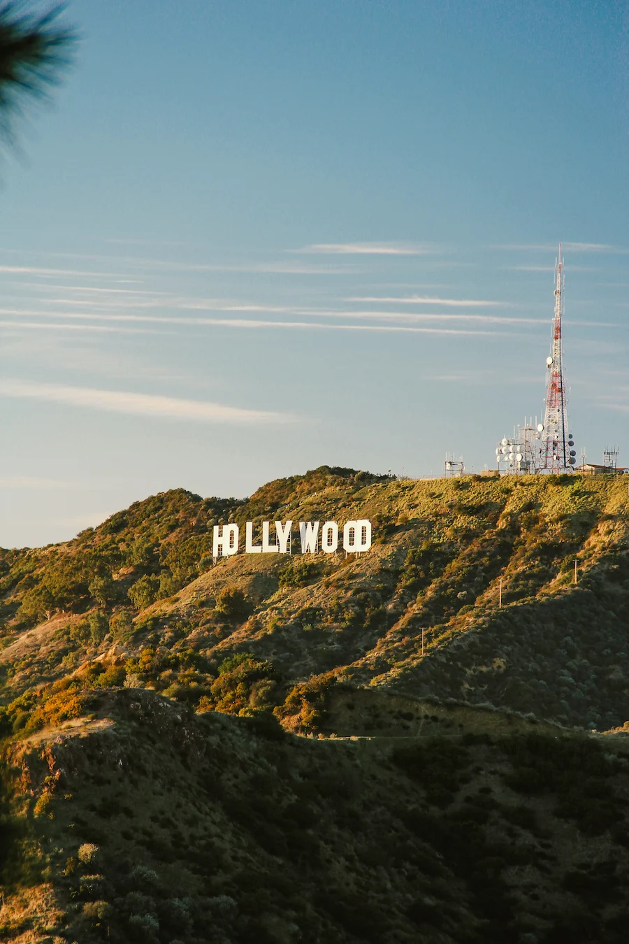 Hollywood Sign overlooking Los Angeles on a hillside, with clear sky and radio towers above.