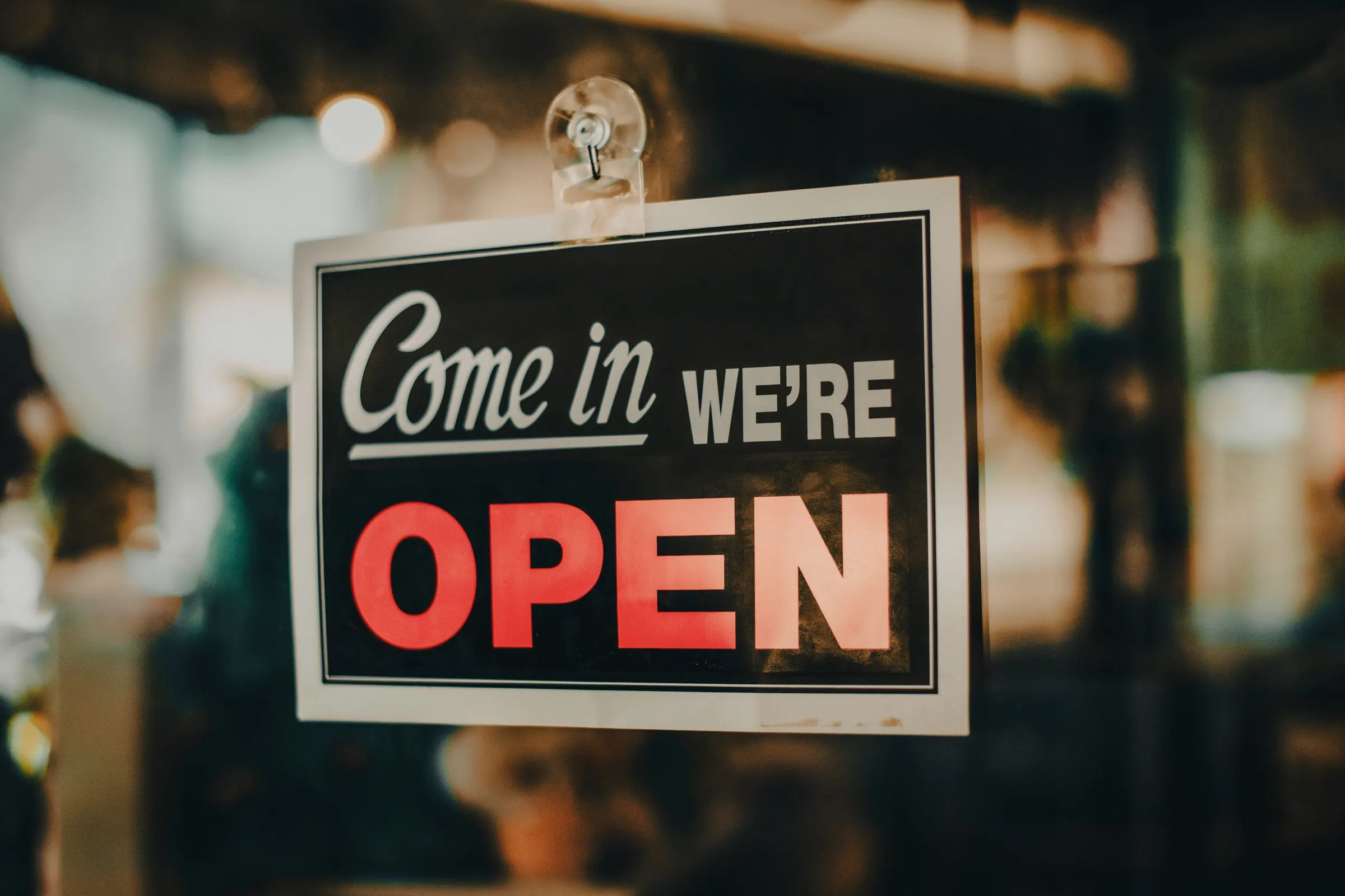 "Come in, we're open" sign hanging in a business window