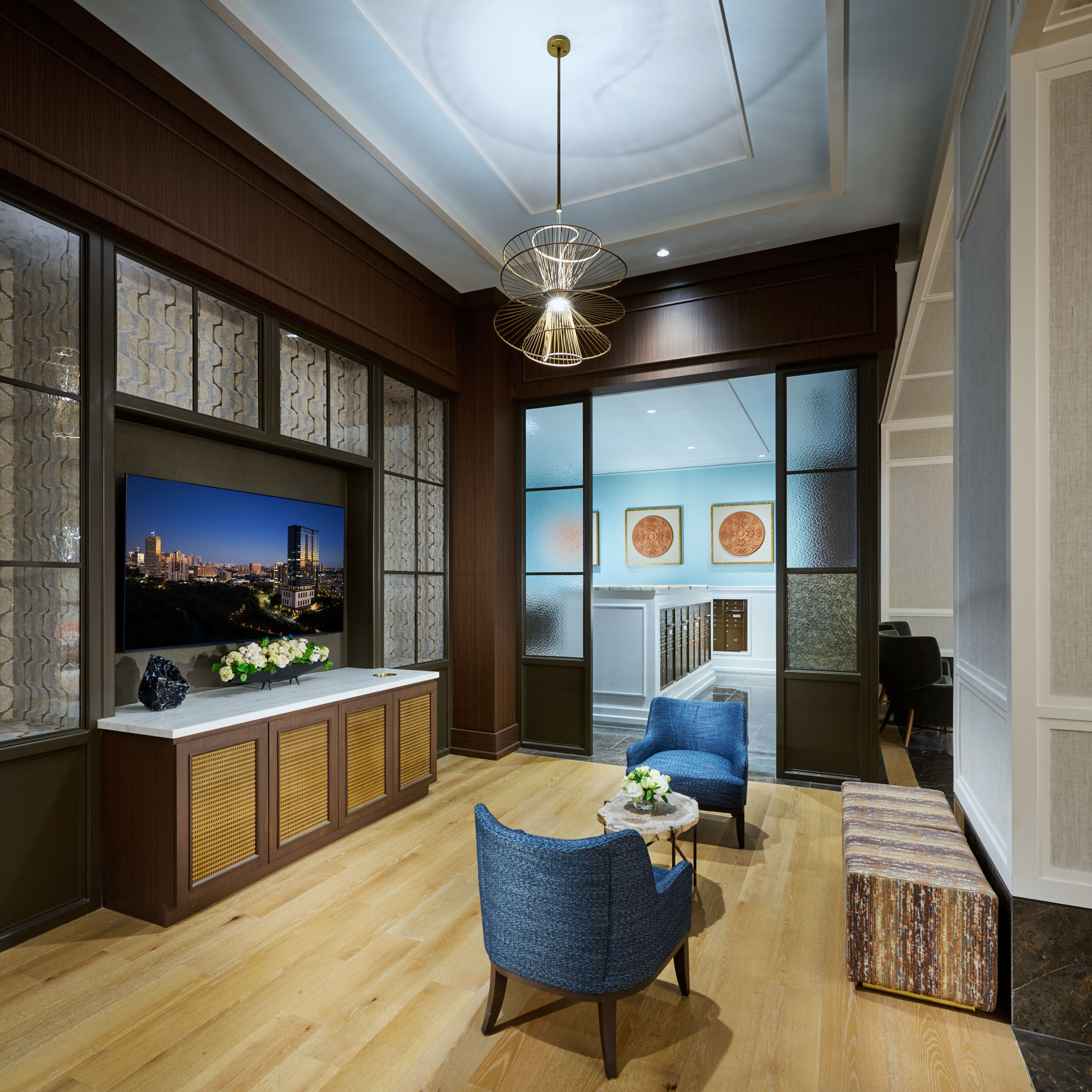 Lounge area with blue chairs and a modern chandelier