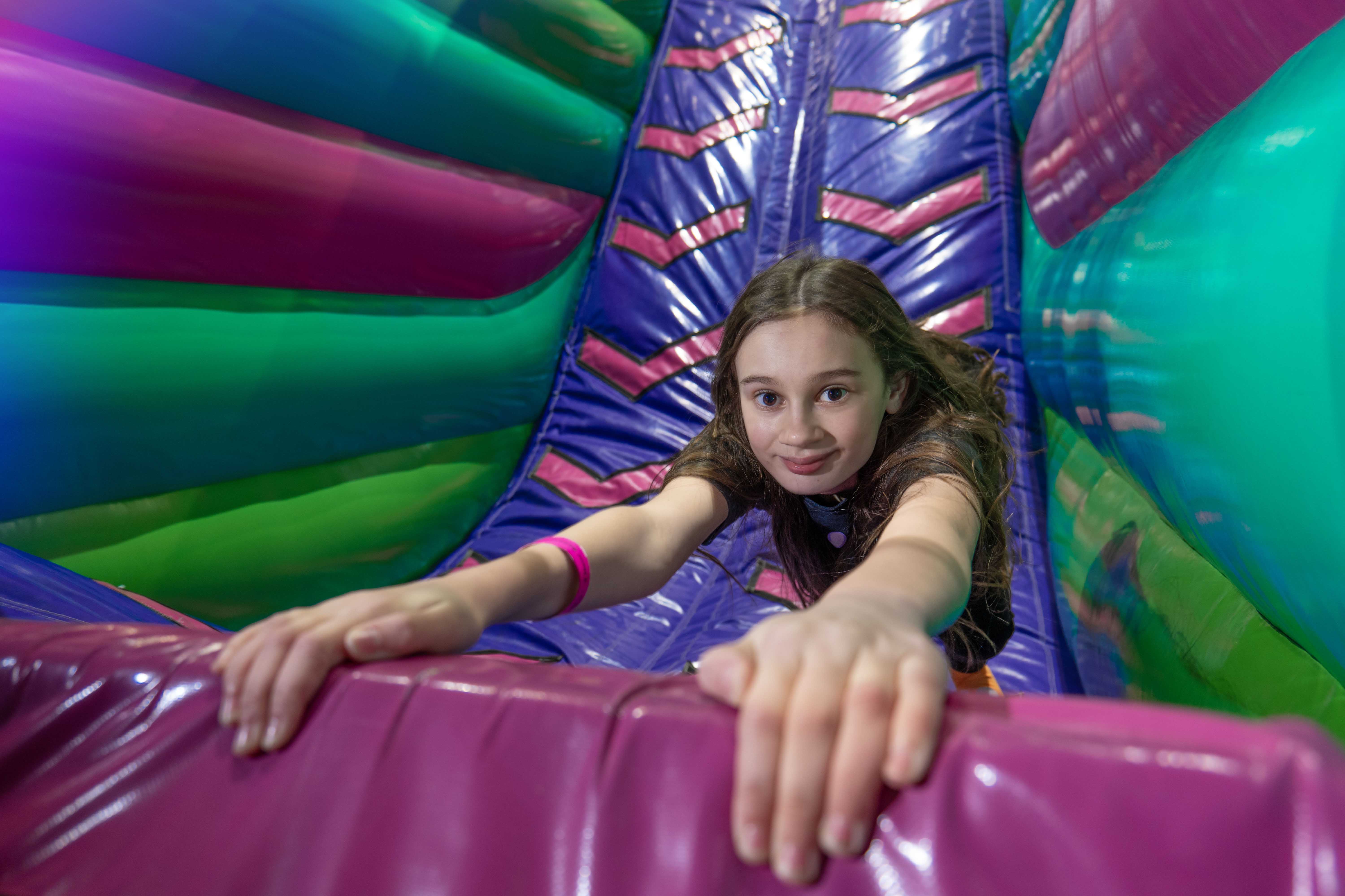 young girl hangin onto brigh coloured inflatables.