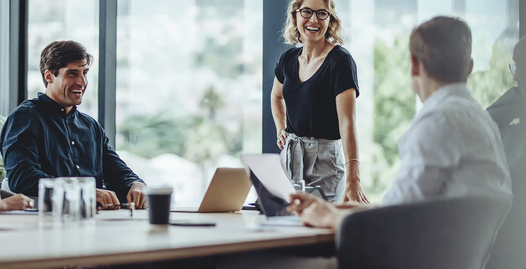 Besprechungssituation, stehende Frau stützt sich auf Schreibtisch