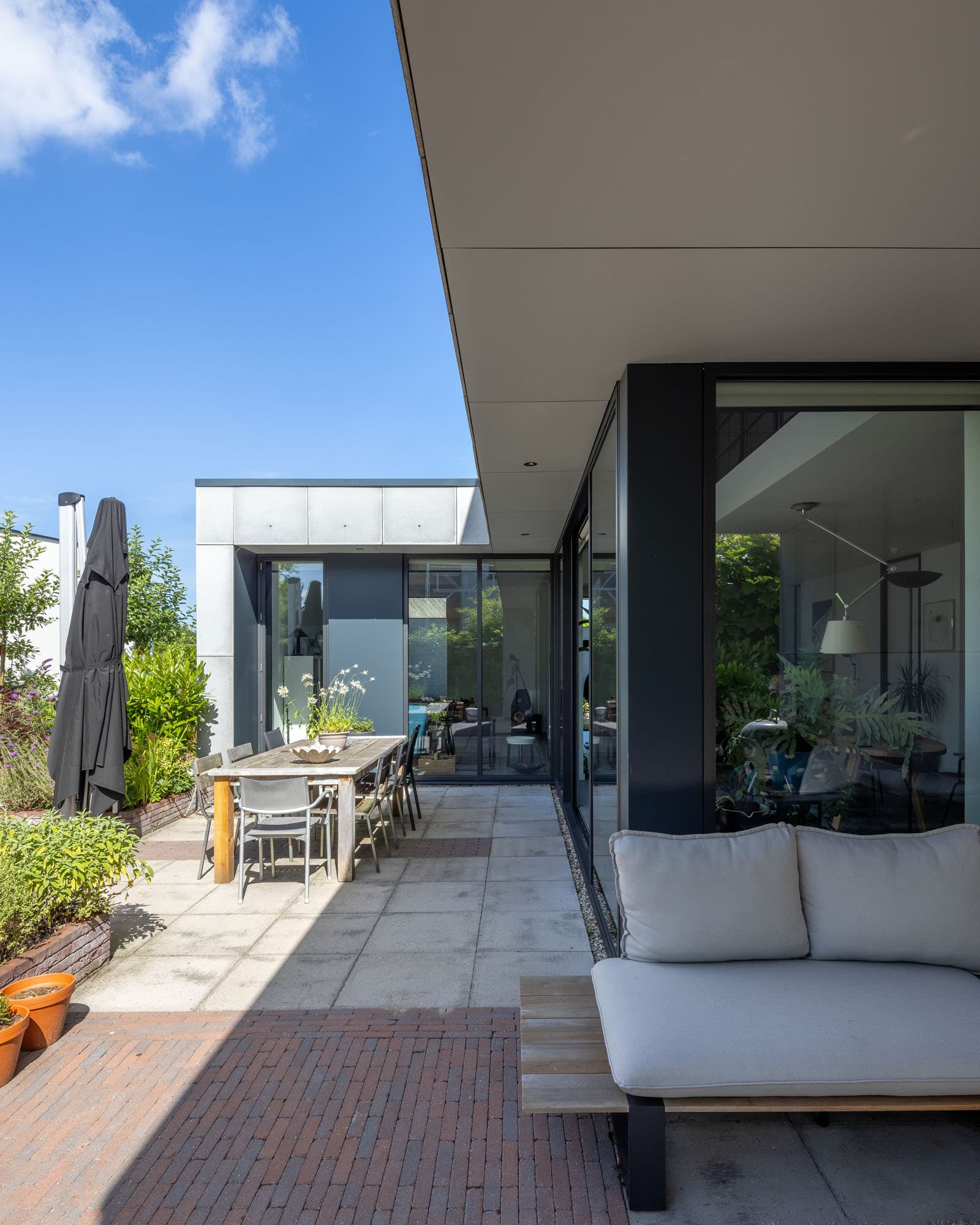 Beschut terras van Villa Rijswijk met overstek, loungehoek en zicht op de tuin.