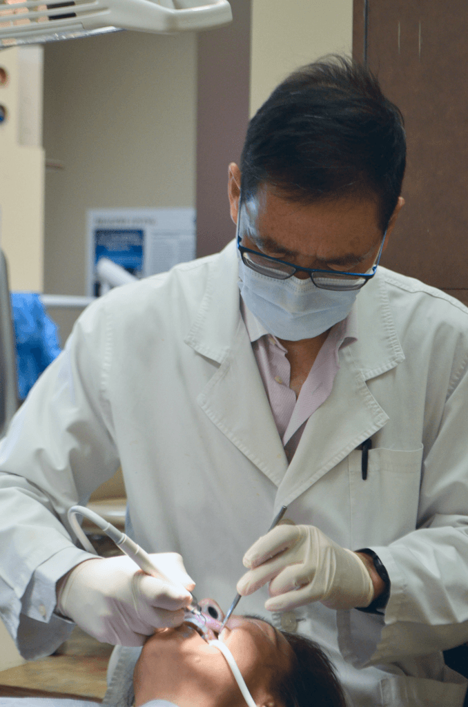 A close-up of a dentist performing a dental procedure on a patient, using various dental instruments.