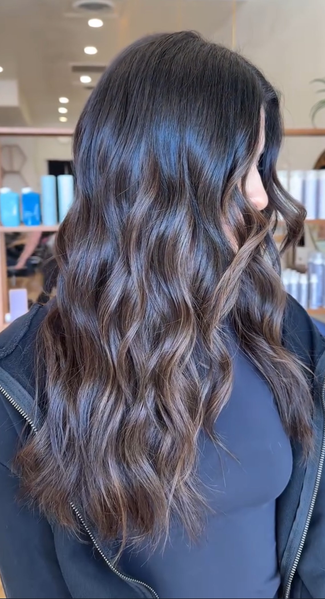 Side view of long, dark brunette hair with subtle dimension, styled in effortless beachy waves for a natural, lived-in finish.