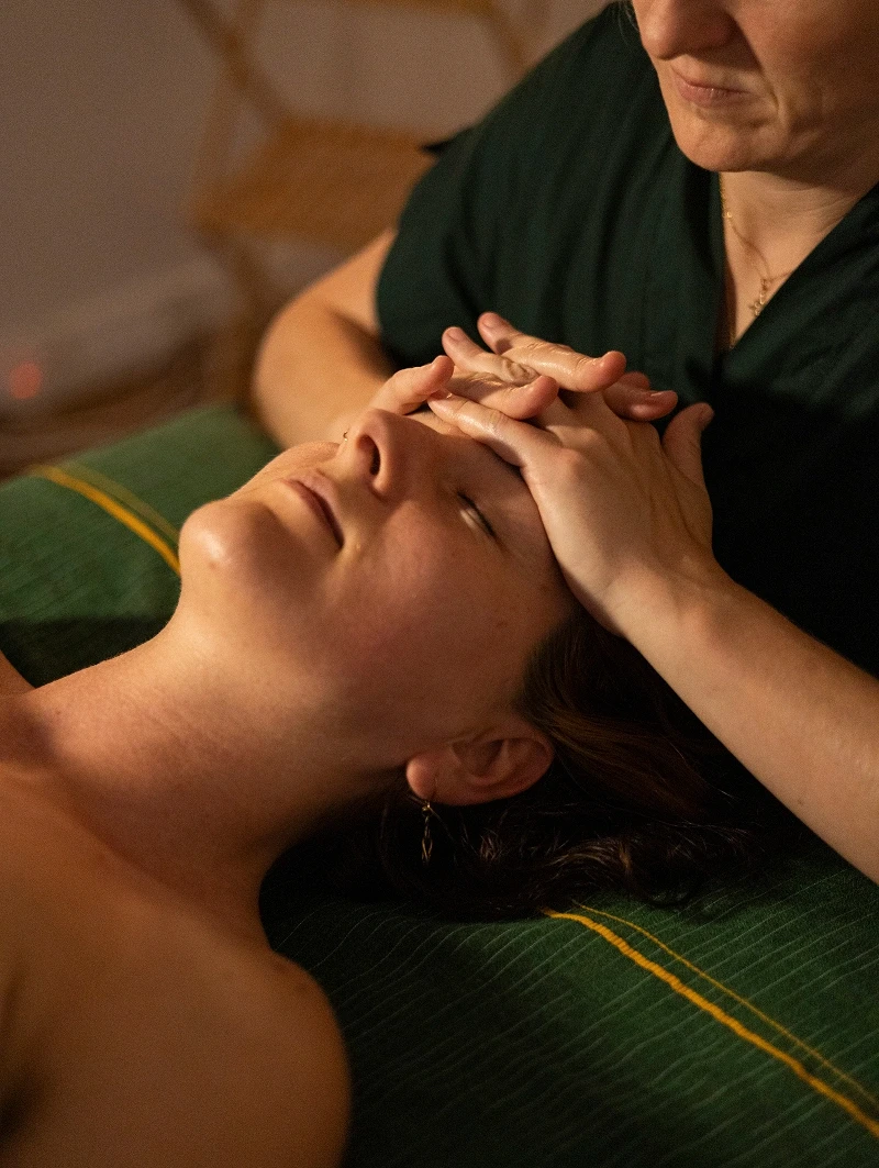 Amy réalise un massage du visage à une cliente allongée