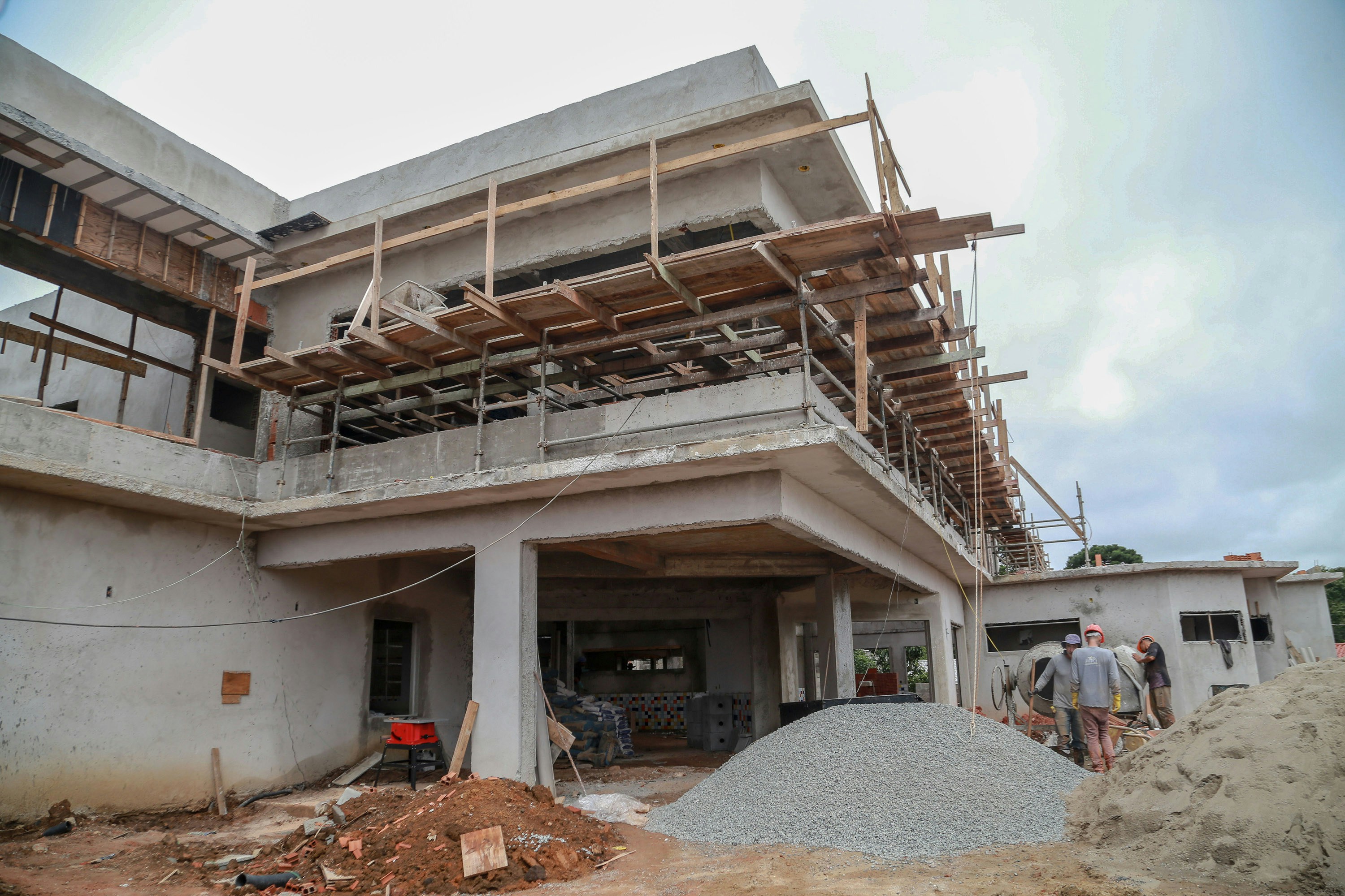 woman in blue jacket and blue denim jeans standing on brown wooden bridge
