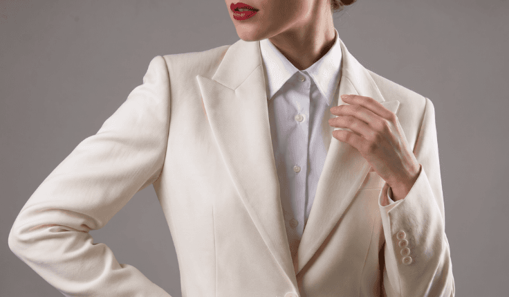 Woman wearing a cream tailored blazer with clean structured shoulders and notch lapels