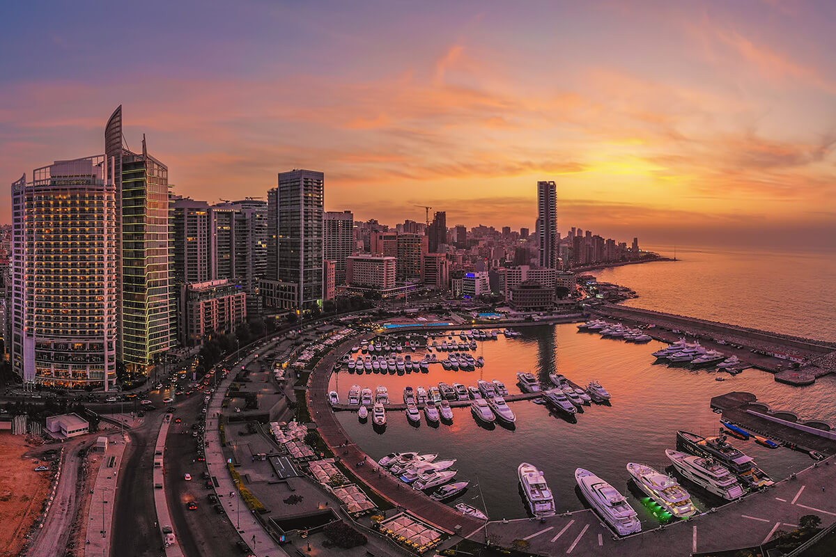 A tranquil canal in Amsterdam reflects historic buildings and the autumn-colored trees under a pastel sky with birds flying above; capturing the serene beauty and cultural architecture of the city.