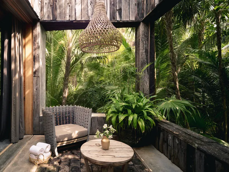 Aire Suite at Be Tulum with second-floor terrace, seating area, and hanging lamp among the greenery.