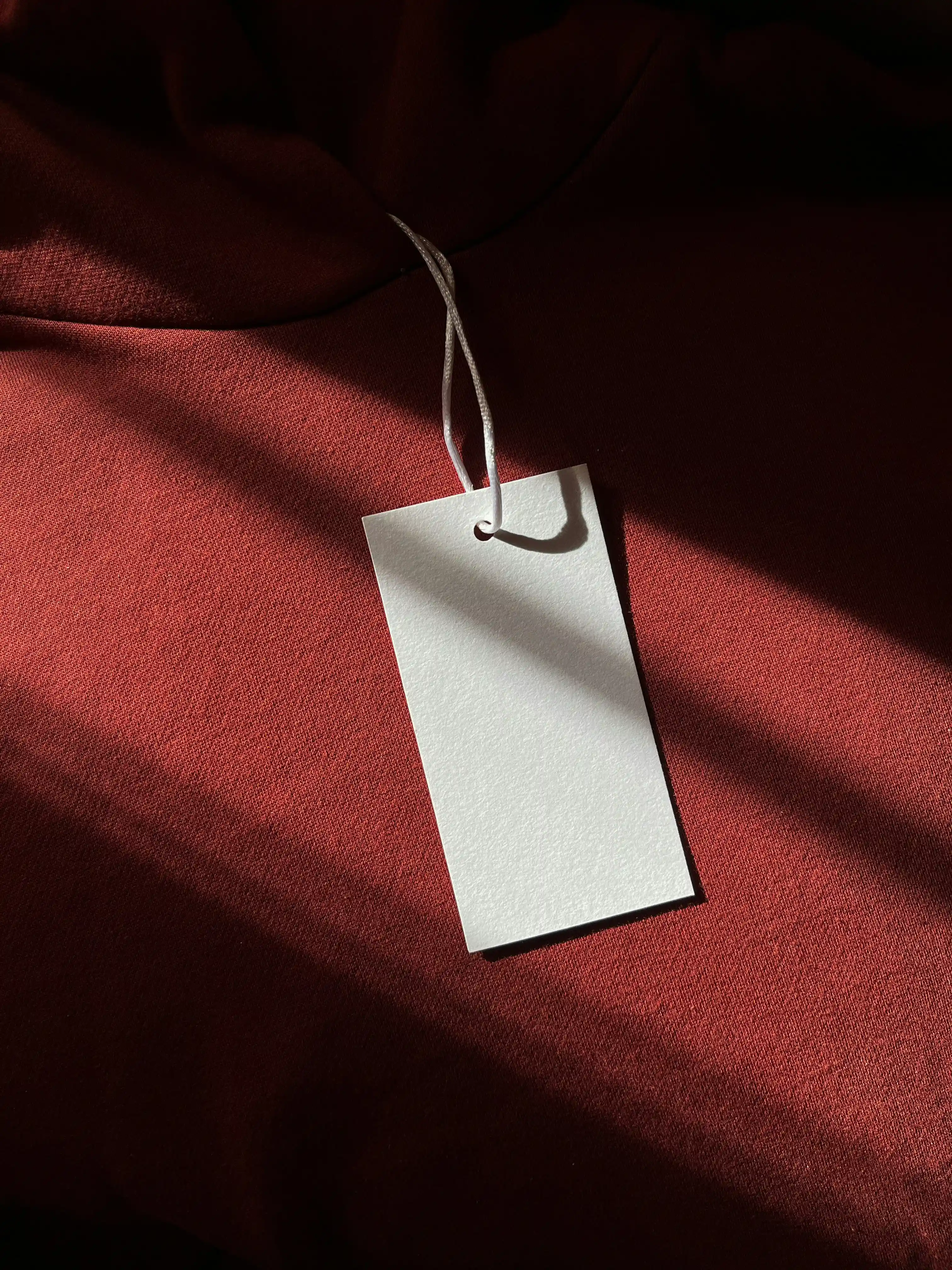 Empty clothing tag on the dark red background.