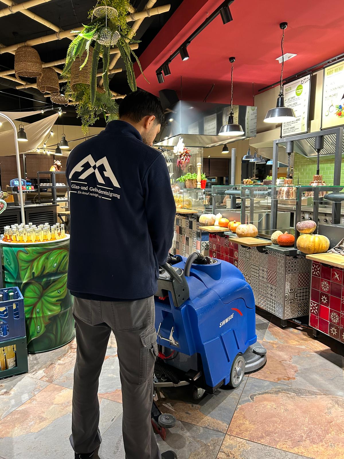 Mitarbeiter von A & A Glas Gebäudereinigung Emsdetten reinigt mit einer Maschine den Boden