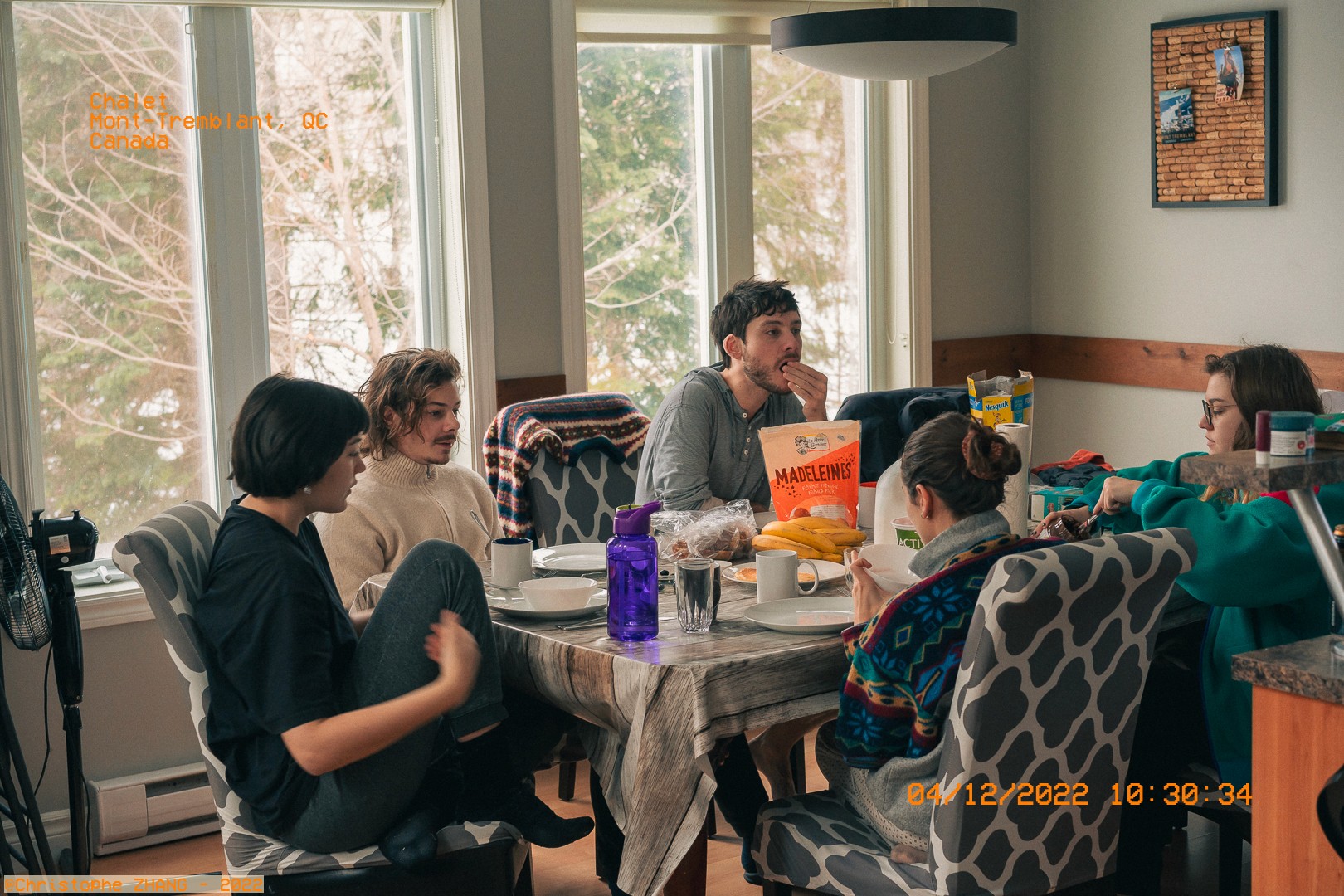 Scène conviviale de petit-déjeuner en intérieur avec vue sur la forêt hivernale, Mont-Tremblant, QC.