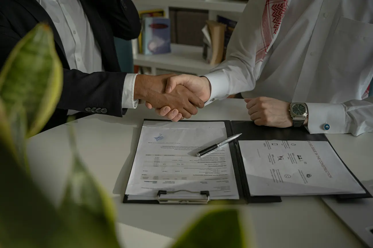 Business handshake over signed documents for a white label agreement