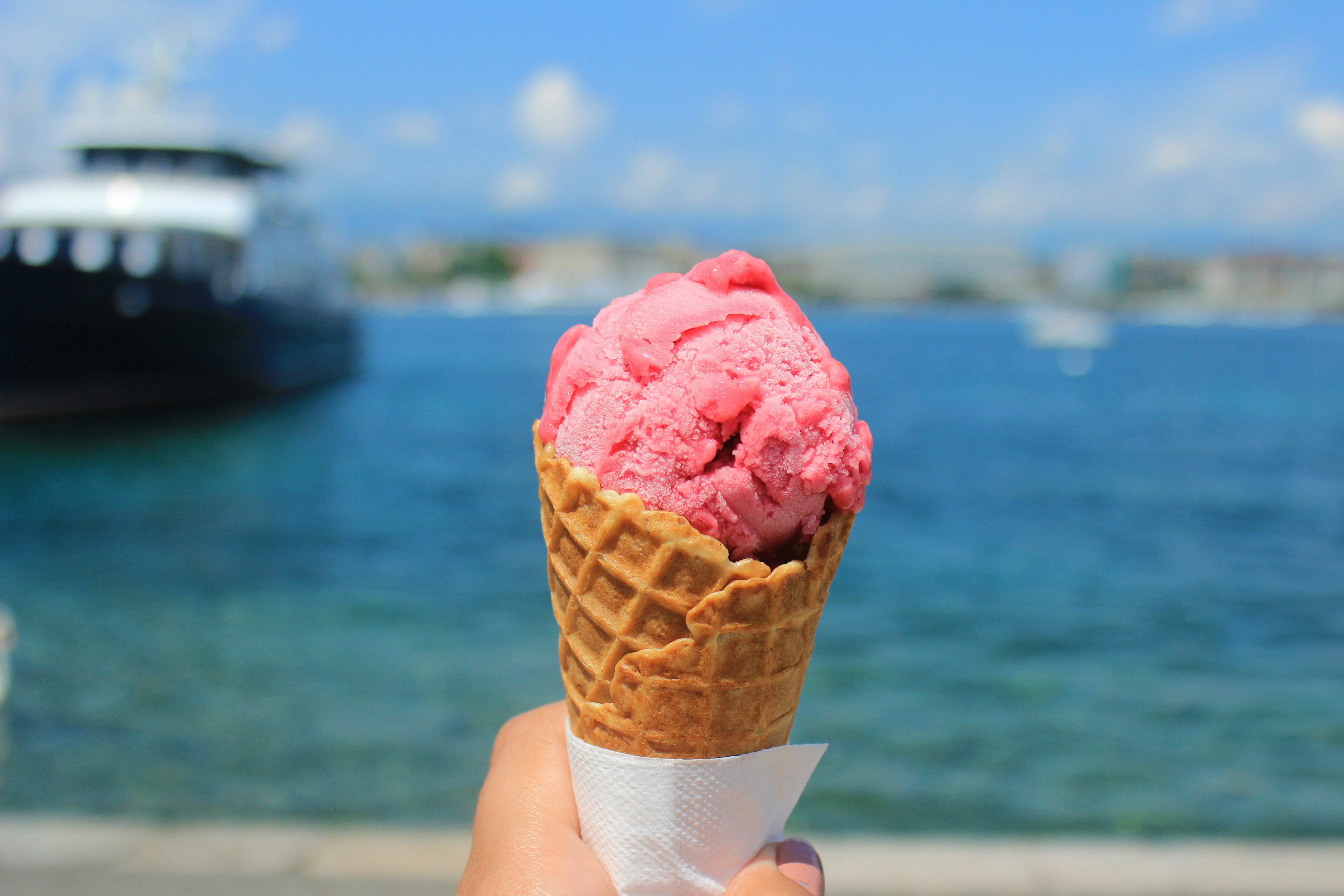 Hand holding an ice cream cone by the waterfront