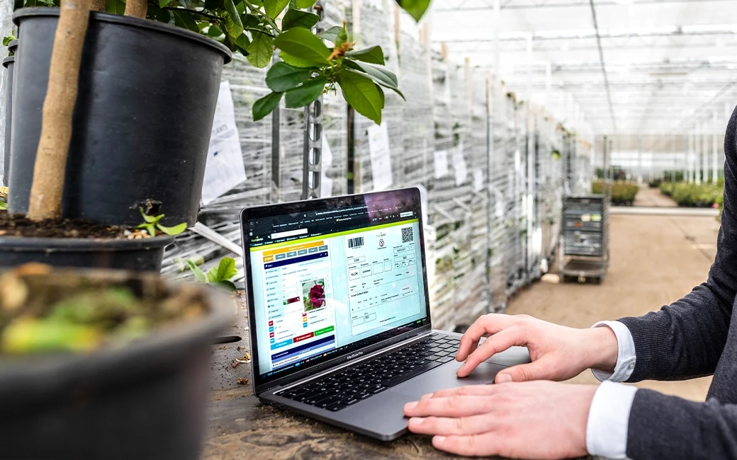 Close up view of laptop showing FreshPortal System inside a greenhouse