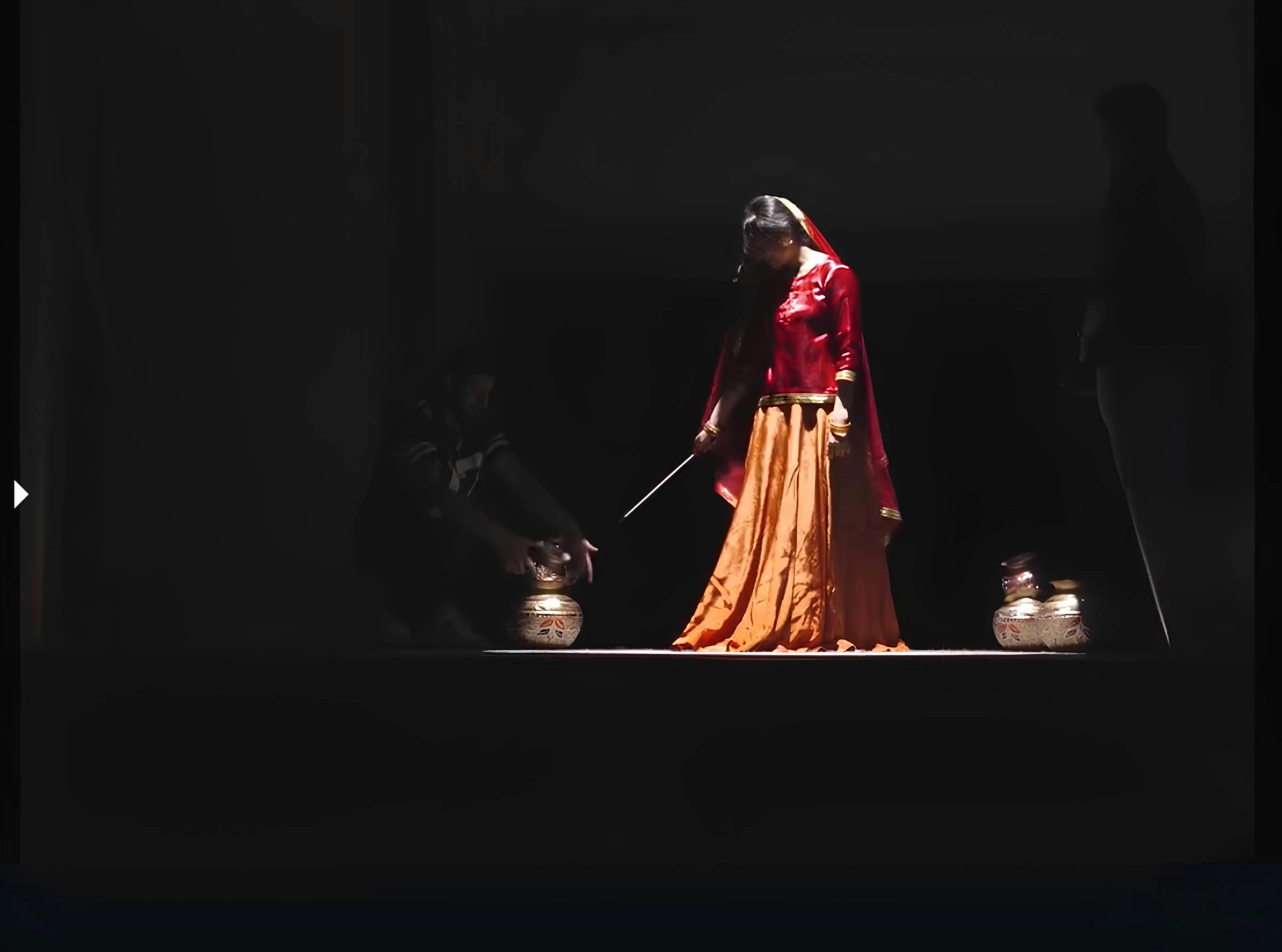 Dramatic stage scene with performers in costume illuminated by warm spotlights for a process documentary.